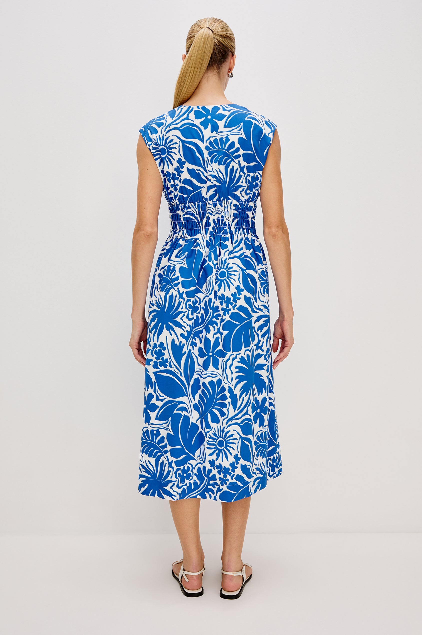 Roxanne A-Line Midi Dress with Smocked Waist, V-Neck, Cap Sleeve and Side Pockets in Blue Riviera Colorway. Full Body Back View Shown on Model.