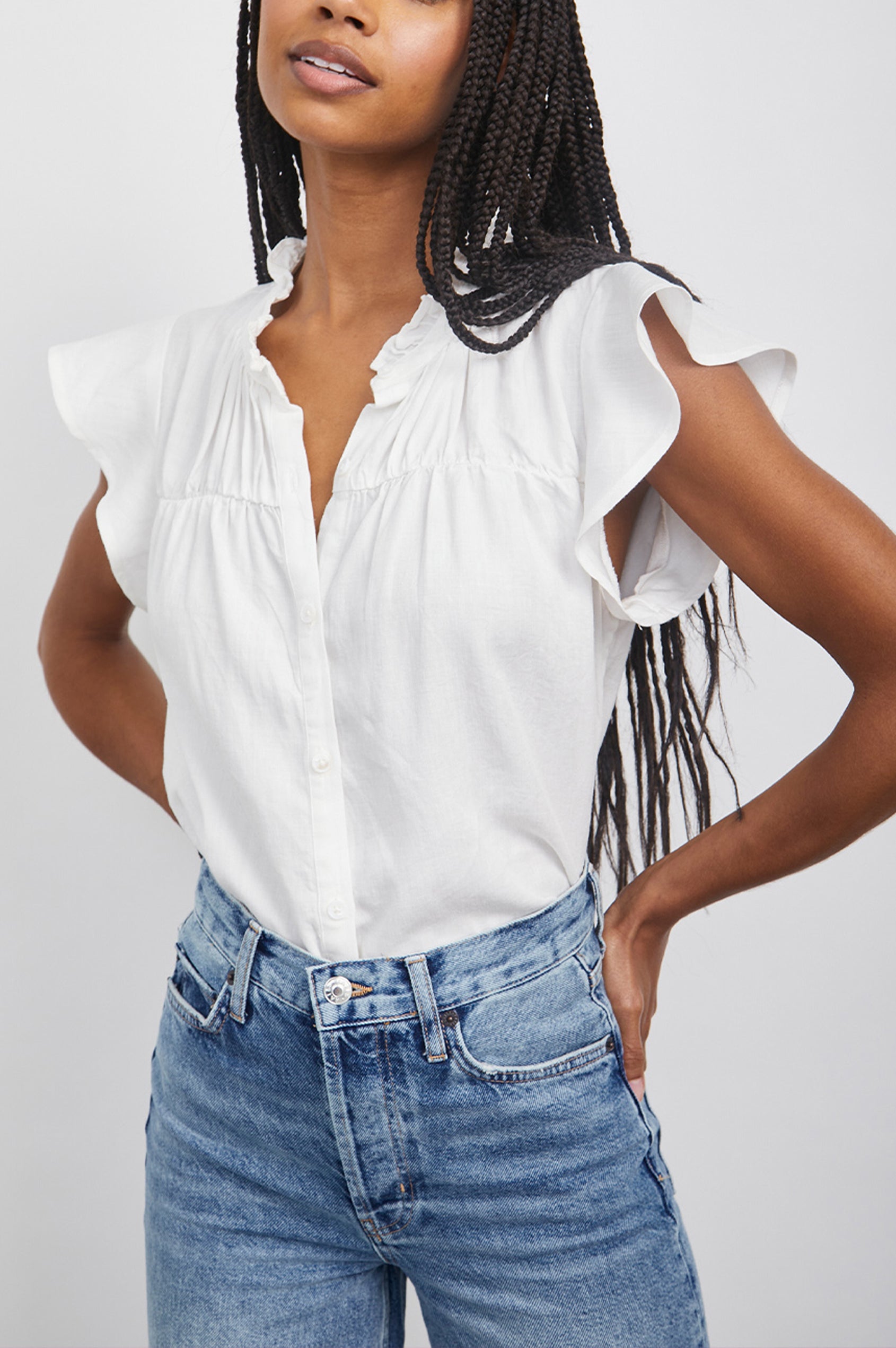 Ruthie Top with Flutter Cap Sleeves, a Ruffled Banded Collar, Buttons Down the Front, and Soft Shirring at Front Yoke in White Colorway - Front Tucked View Featured on Model