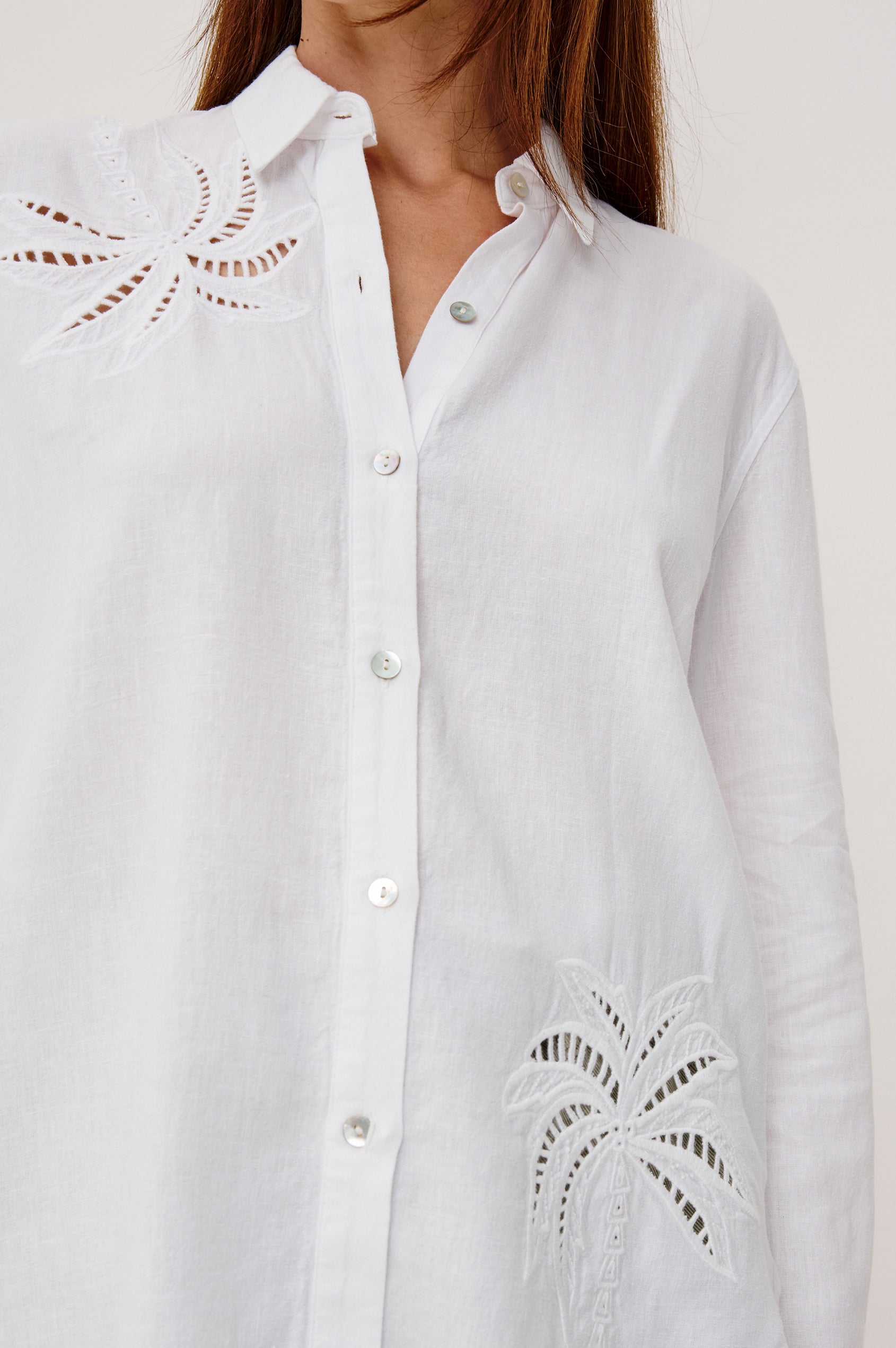 Samar Button-Up Collared Shirt in Linen With Palm Tree Eyelet Embroidery, Relaxed Fit, and Long Sleeves in White Palm Embroidery Colorway - Upper Body Front Close Up View Featured on Model