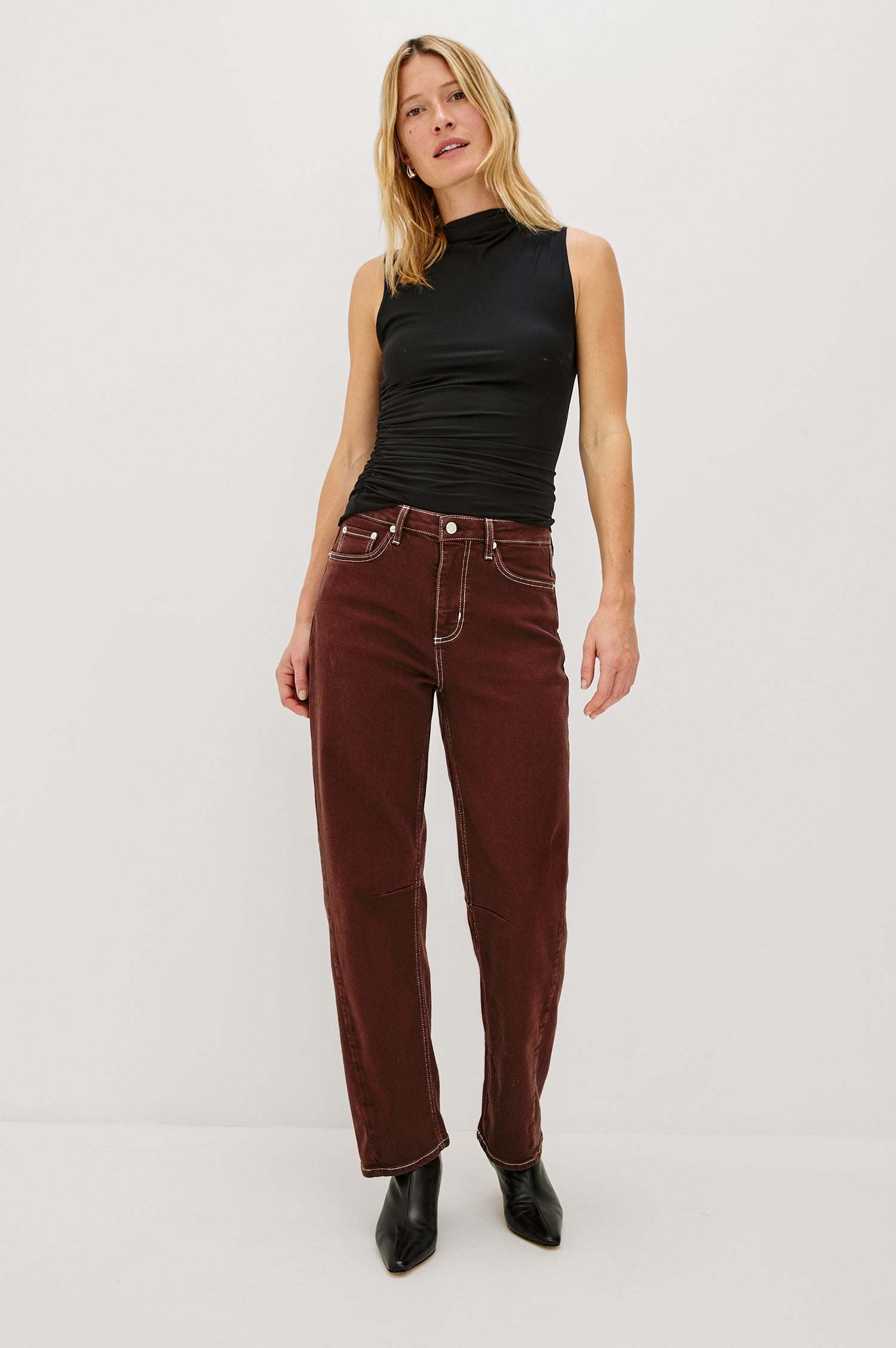 The Samo is a denim barrel leg jean, it features a low-slung fit in light-stretch denim with darting details and a subtle curved seam in Chocolate Contrast Stitch colorway. Front view featured on model.