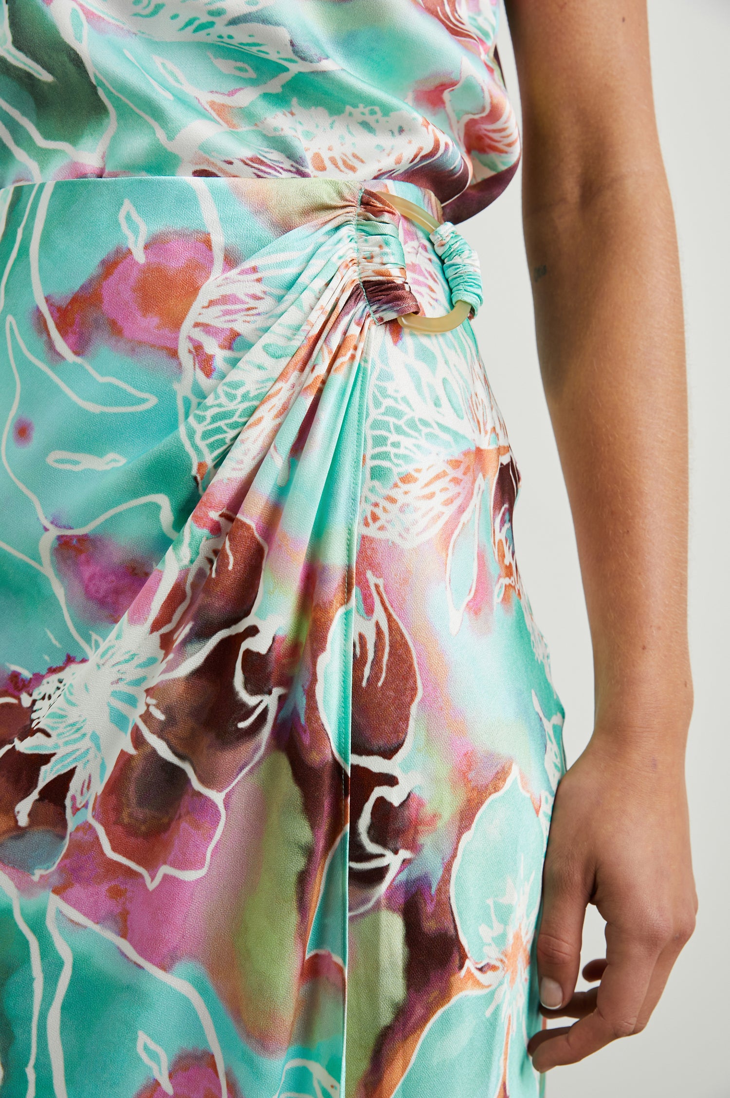 Sampha Faux Wrap Midi Skirt with a D Ring Horn Faux Closure in Kauai Floral Colorway, Flowers in Pinks, Browns, Blues, Greens and White - Front View Featured on Model 