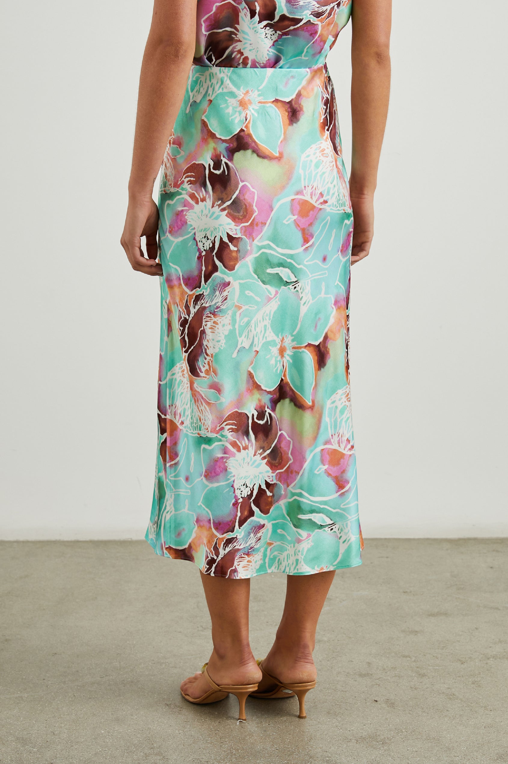 Sampha Faux Wrap Midi Skirt with a D Ring Horn Faux Closure in Kauai Floral Colorway, Flowers in Pinks, Browns, Blues, Greens and White - Back View Featured on Model 
