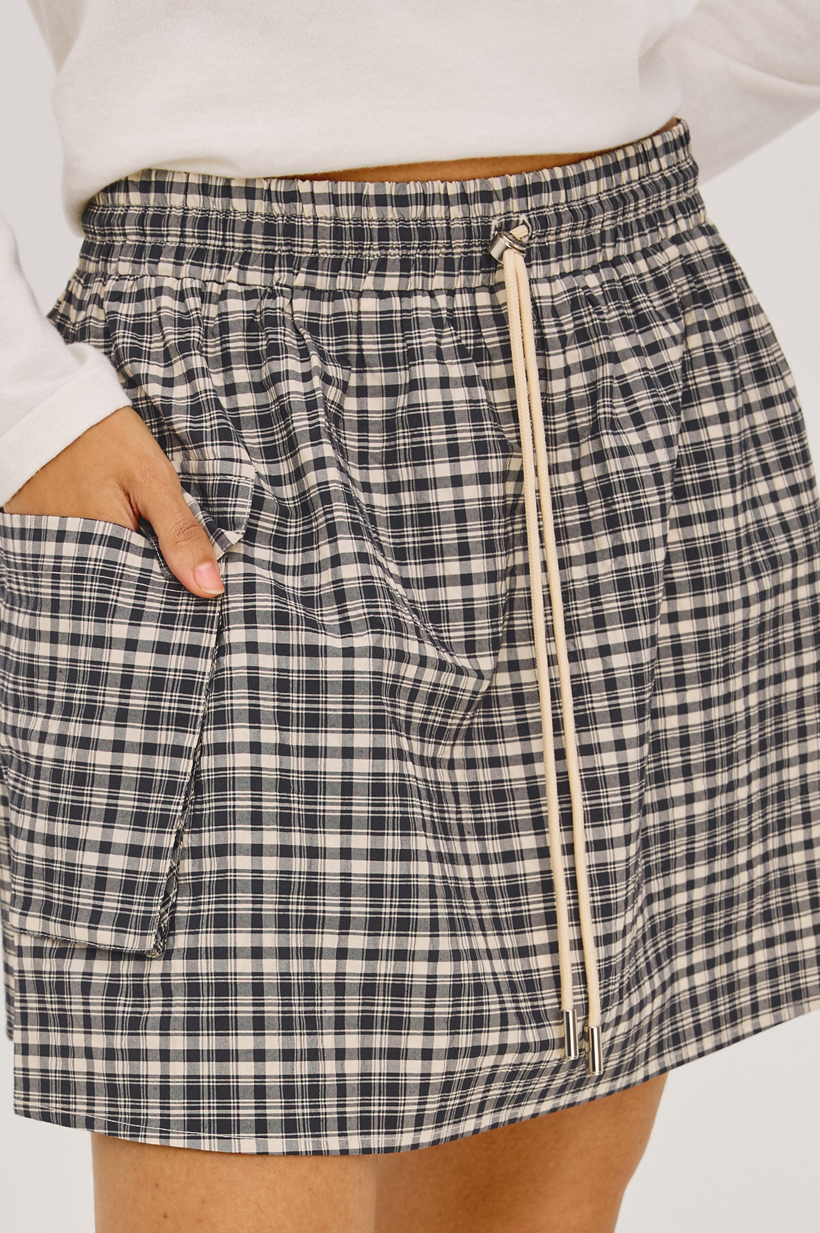 Sayana Mini Skirt in Crinkle Nylon With High-Waisted Fit, Elastic Drawcord Waist, Side Flap Pocket, and Full Lining in Mini Check Colorway - Lower Body Front View Featured on Model