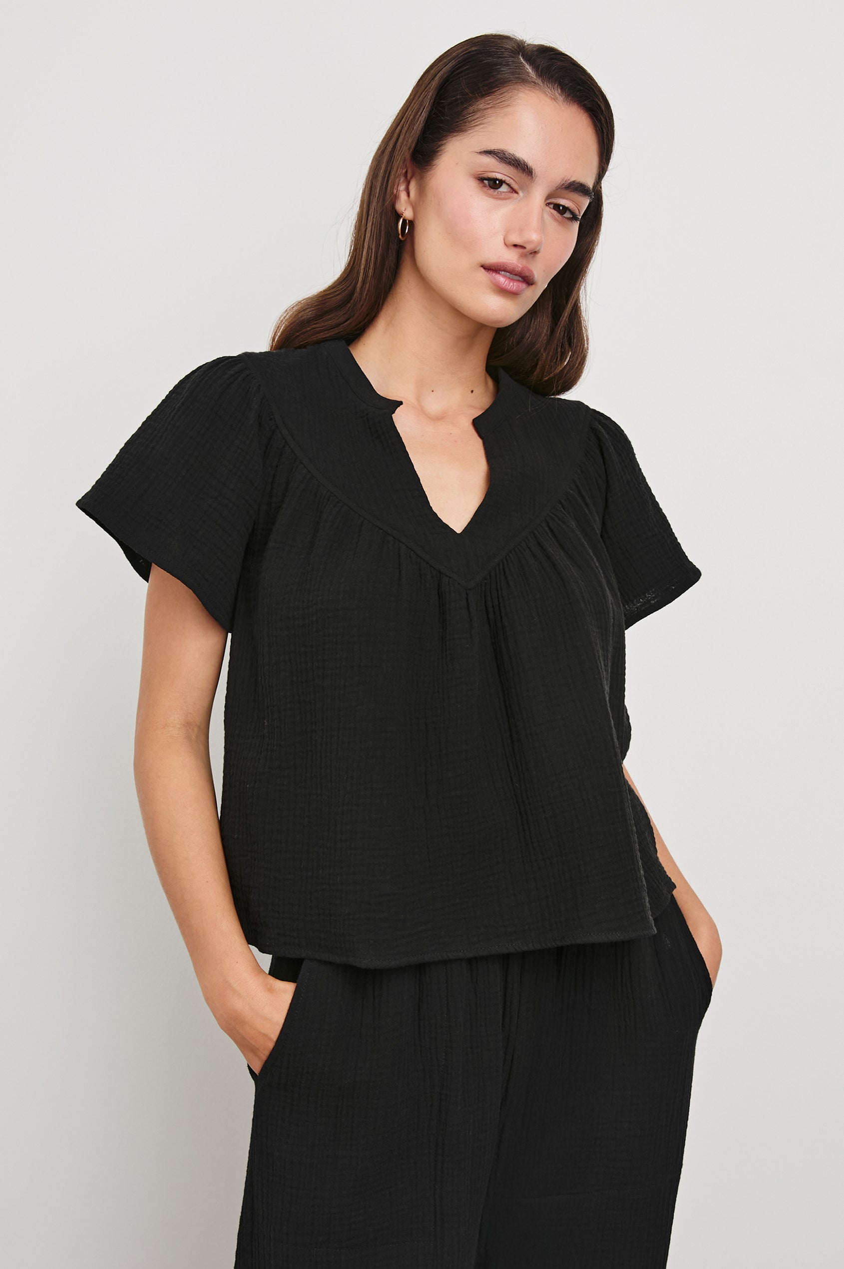 Sayer Short Sleeve Cotton Gauze Top With V-Neck In Colorway Black - Front View Featured On Model Hands In Pockets