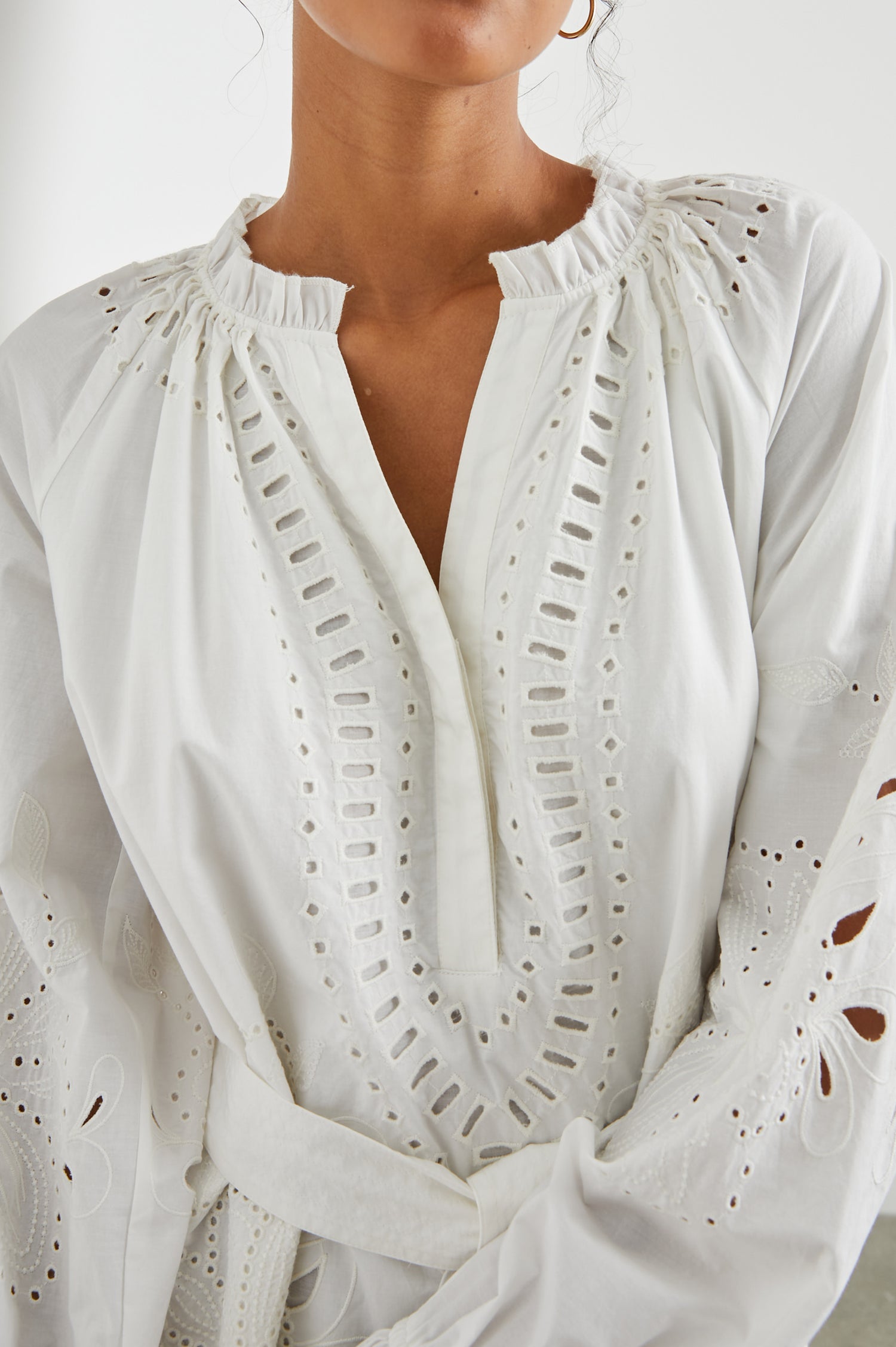 Saylor Long-Sleeve Midi Dress with a Half-Sealed Placket, a V Neck, Ruffled Collar with Shirring, a Fabric Tie Belt, and Floral and Geometric Eyelet Details in White Colorway - Front View Featured on Model 