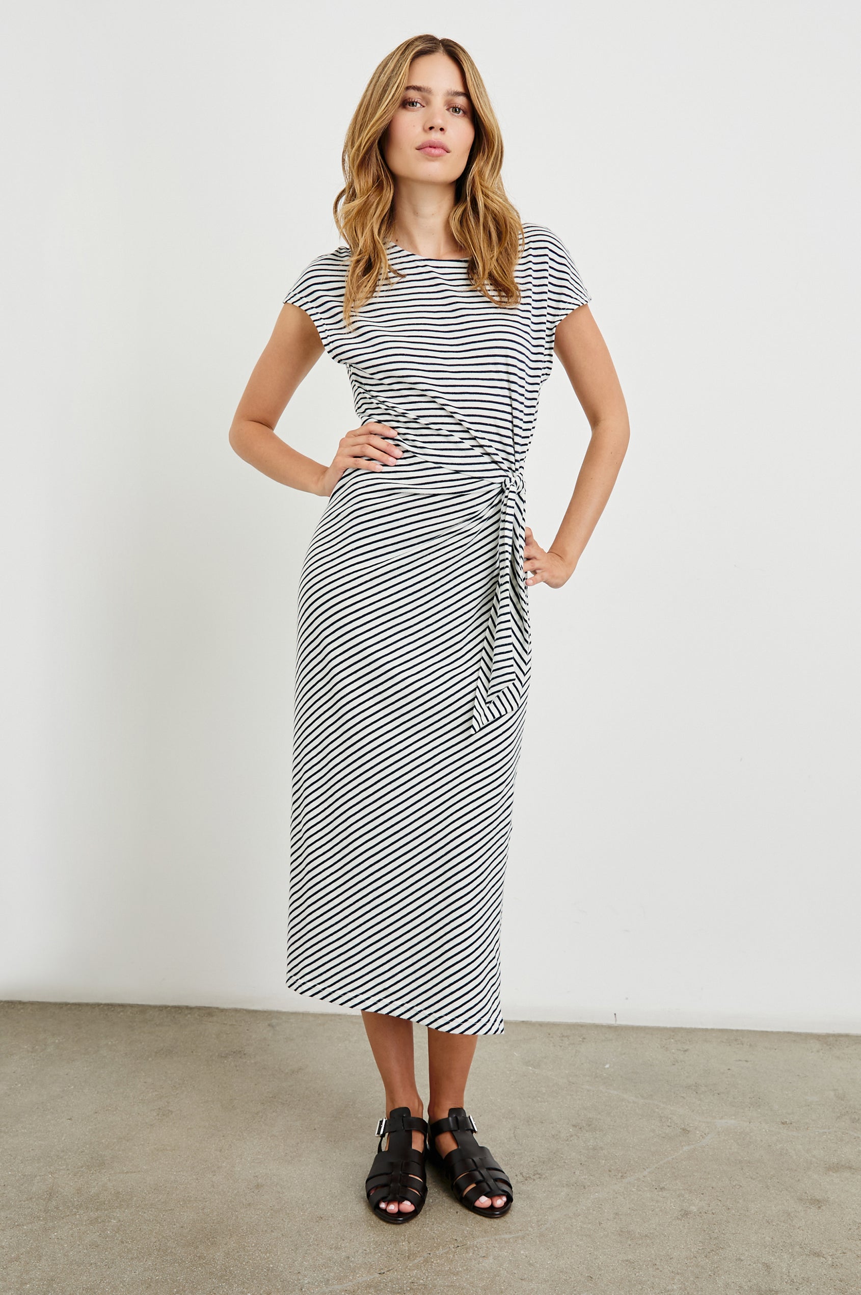 Selah Maxi Dress with Short Sleeves, Boatneck, Adjustable Side Tie at Waist and Two Mid-Calf Side Slits in Black Colorway  - Front Full Body View Featured on Model
