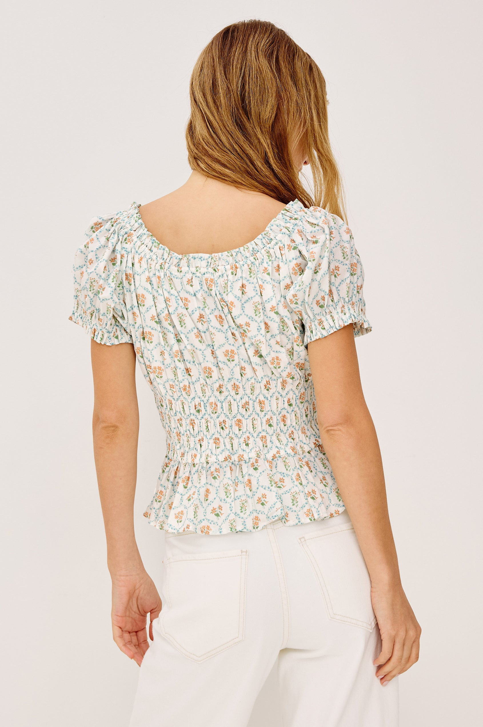 Serena Crop Top in Beach Cotton With Scoop Neckline, Short Puff Sleeves, Center-Front Ties, Smocked Waist, and Flared Peplum Hem in Peach Peony Colorway - Upper Body Back View Featured on Model
