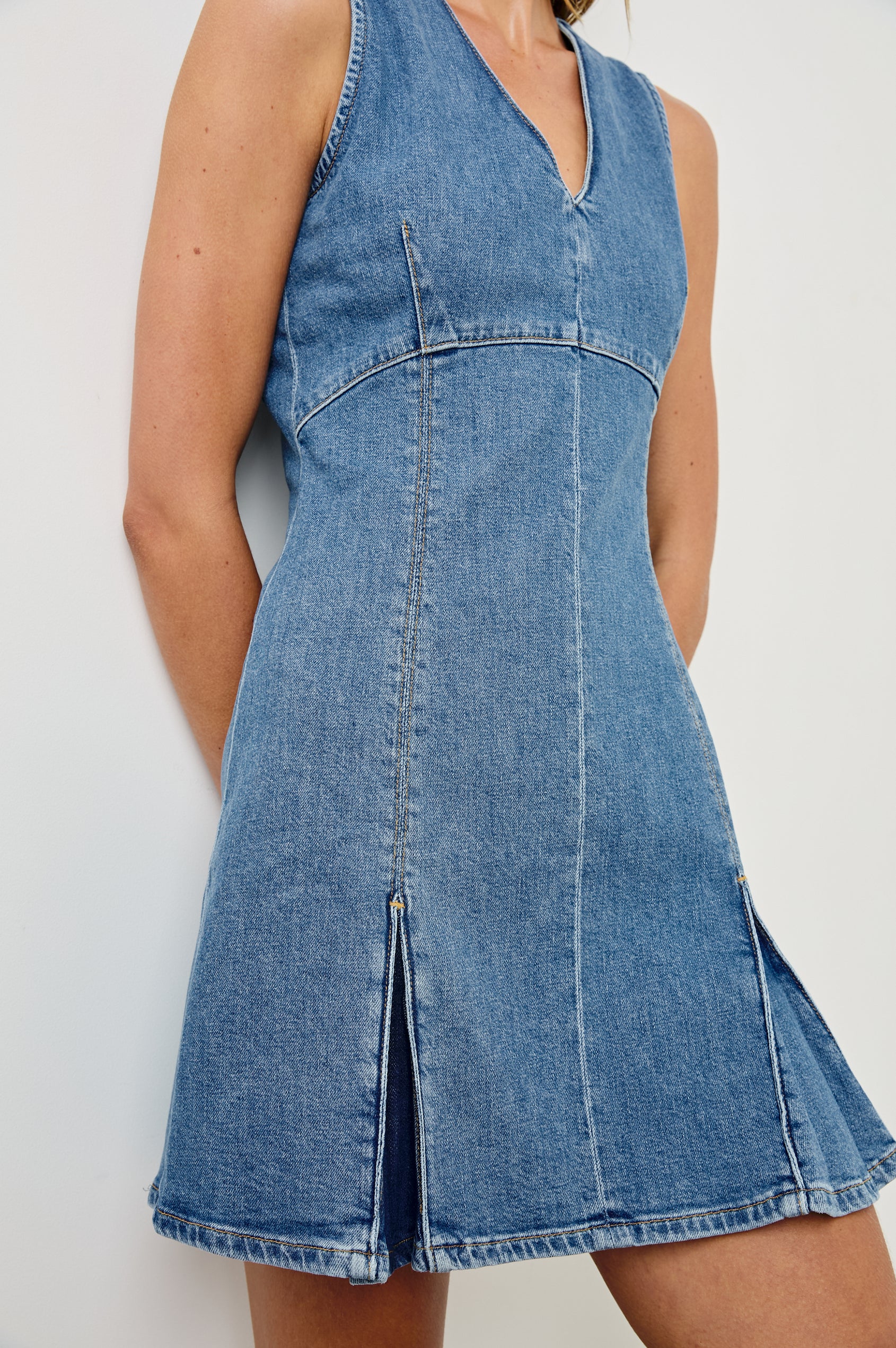Serra fitted v-neck denim mini dress with pleated skirt in light wash Bristol -  close up of details on model