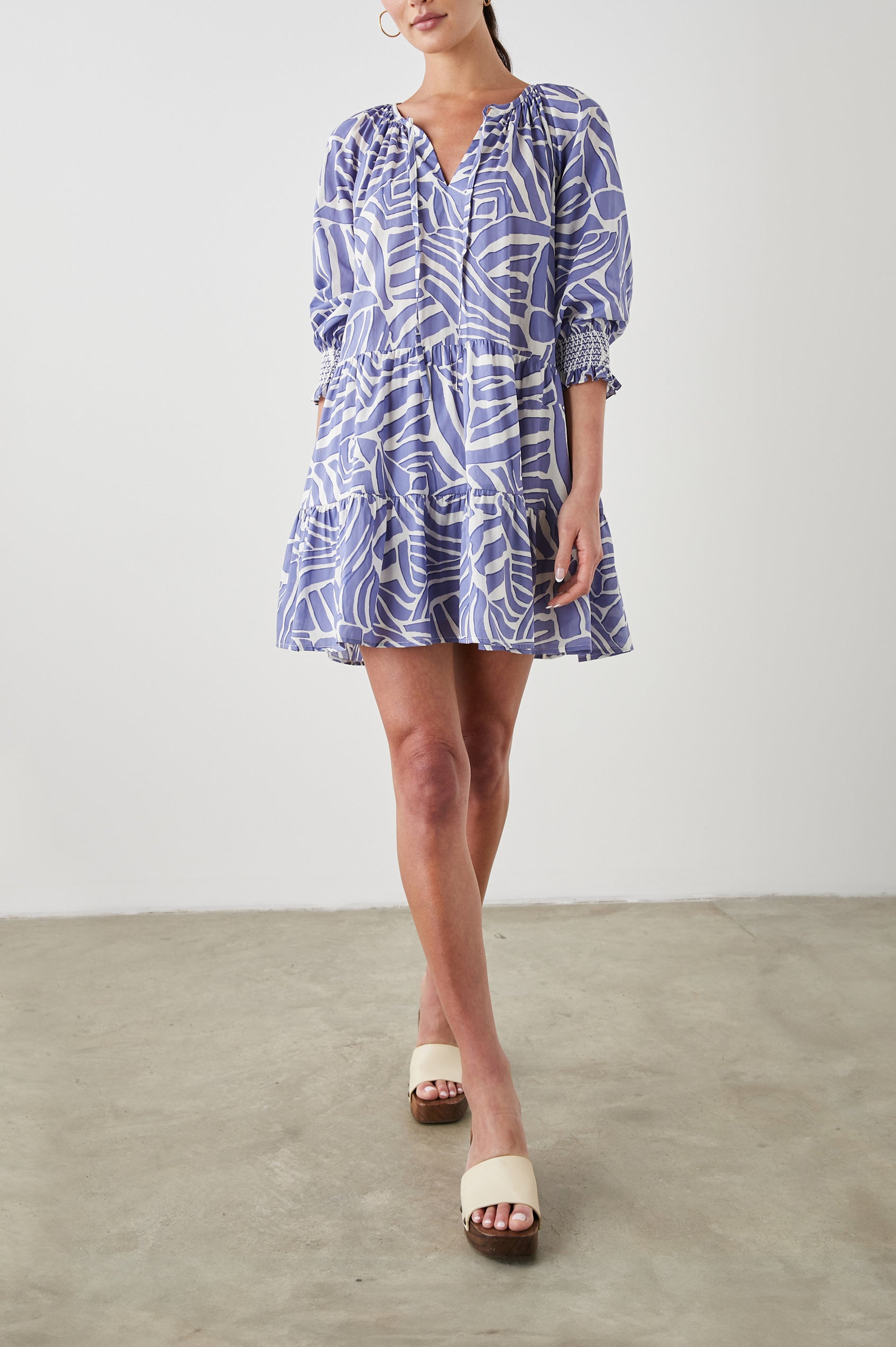 Sia Mini Dress with Three-Quarter Sleeves, Shirred Cuffs, a Tiered Skirt, and a V Neck with a Tie and Light Ruching in Island Waves Colorway, a Purple and White Print - Front Full Body View Featured on Model 