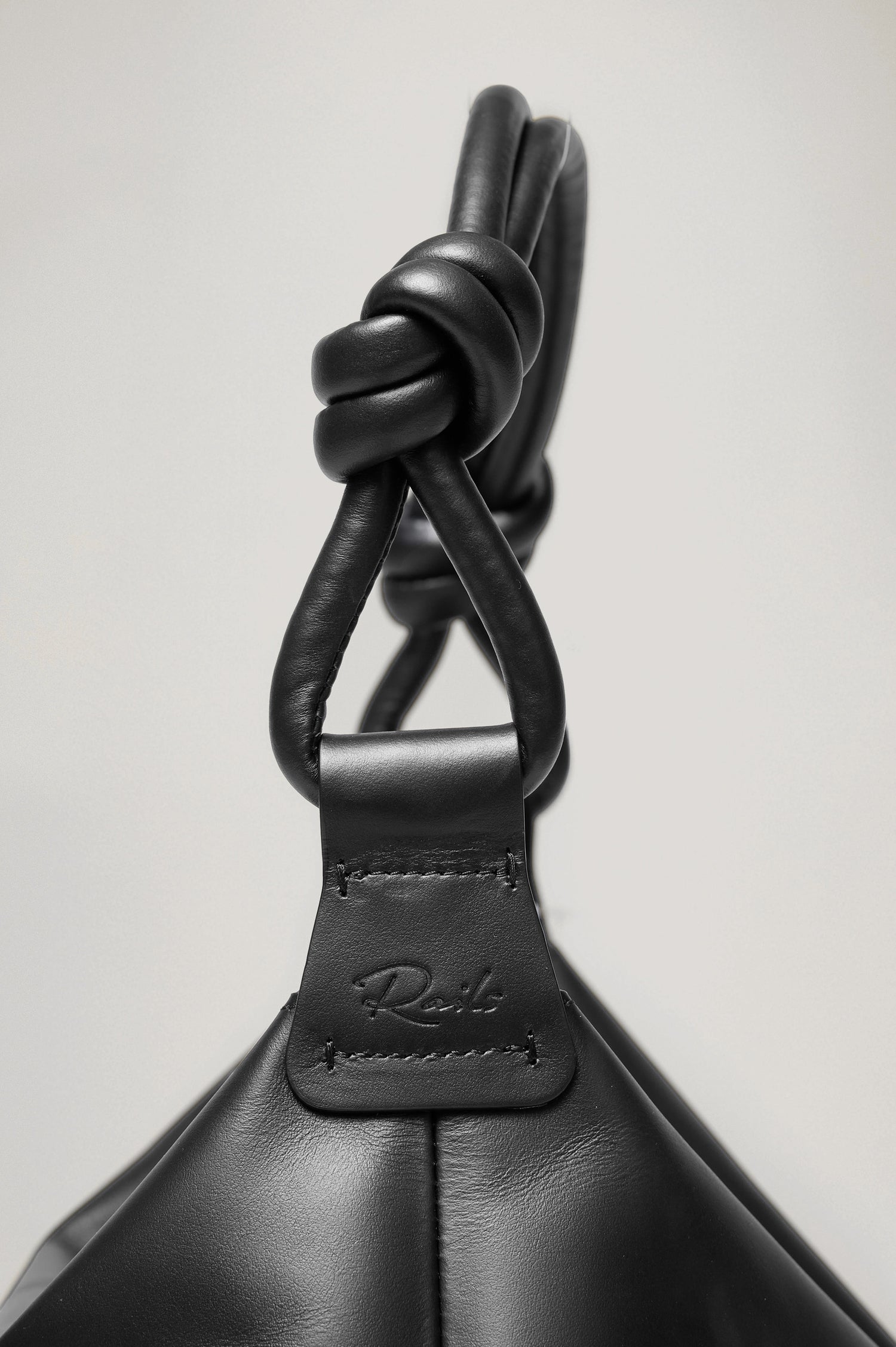 Siena Slouchy Hobo Bag in Italian Leather With Knotted Top Strap, Zipper Closure With Fringe Tassel And Interior Snap Button Slip Pocket in Black Colorway - Close Up Side View Branded Detail Featured