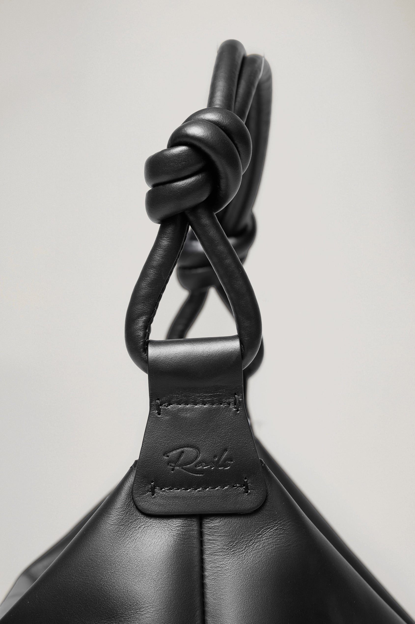 Siena Slouchy Hobo Bag in Italian Leather With Knotted Top Strap, Zipper Closure With Fringe Tassel And Interior Snap Button Slip Pocket in Black Colorway - Close Up Side View Branded Detail Featured