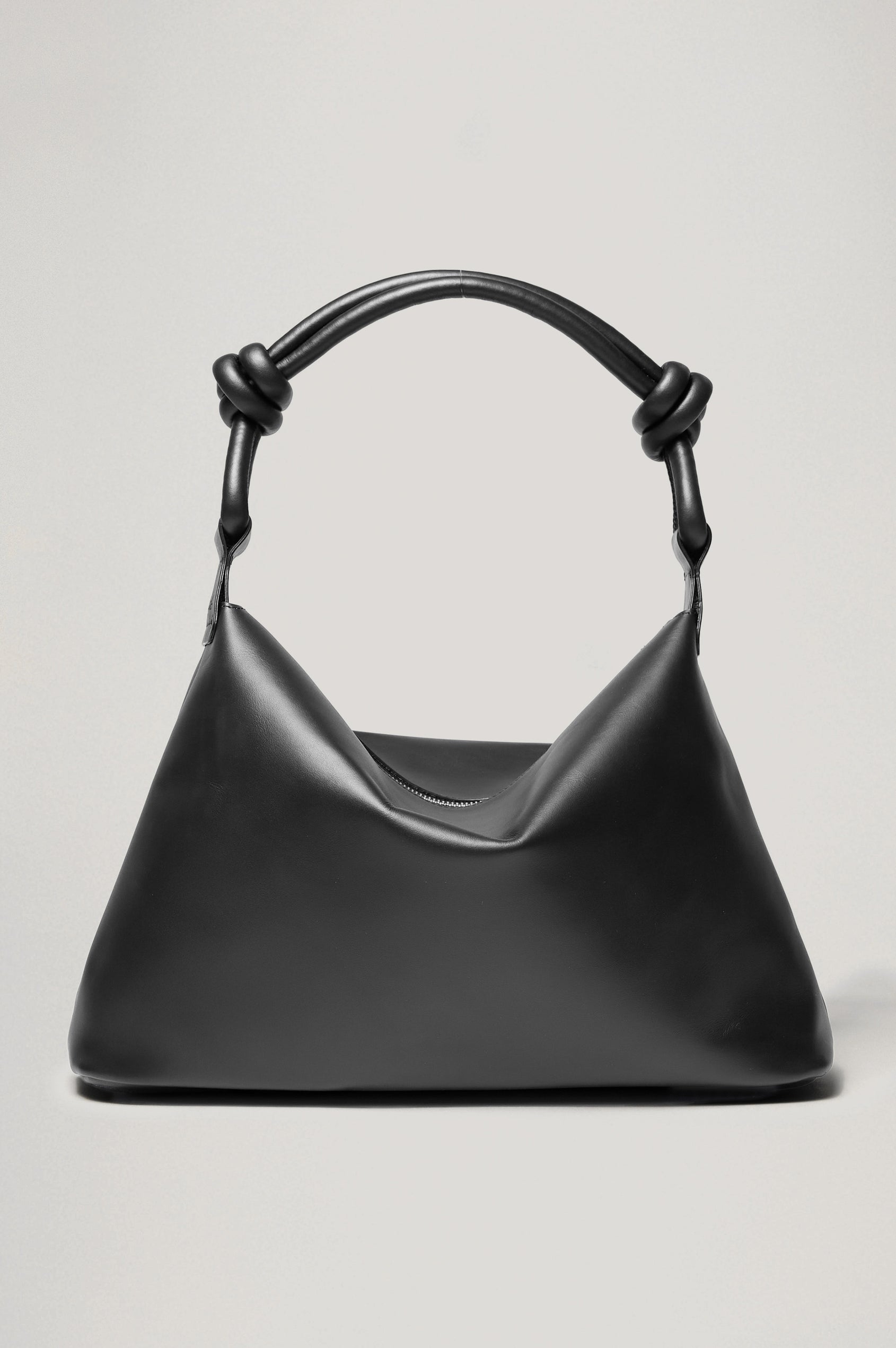 The Siena is a true slouchy hobo bag, crafted from smooth leather with a knotted top strap and a zip closure finished with a fringed tassel. In Black Leather Colorway. Front view featured.