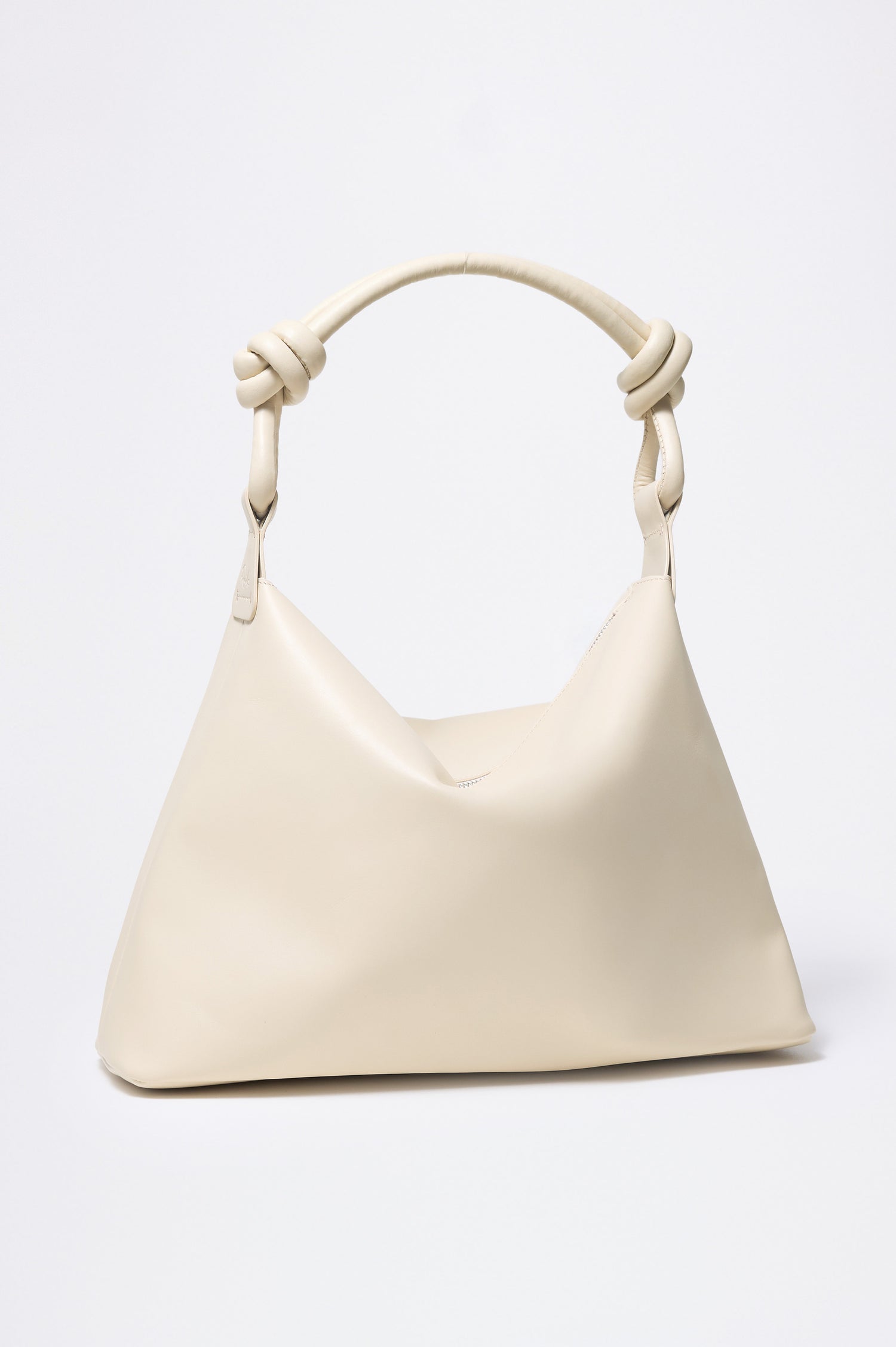 The Siena is a true slouchy hobo bag, crafted from smooth leather with a knotted top strap and a zip closure finished with a fringed tassel. In Bone Leather Colorway. Front view featured.