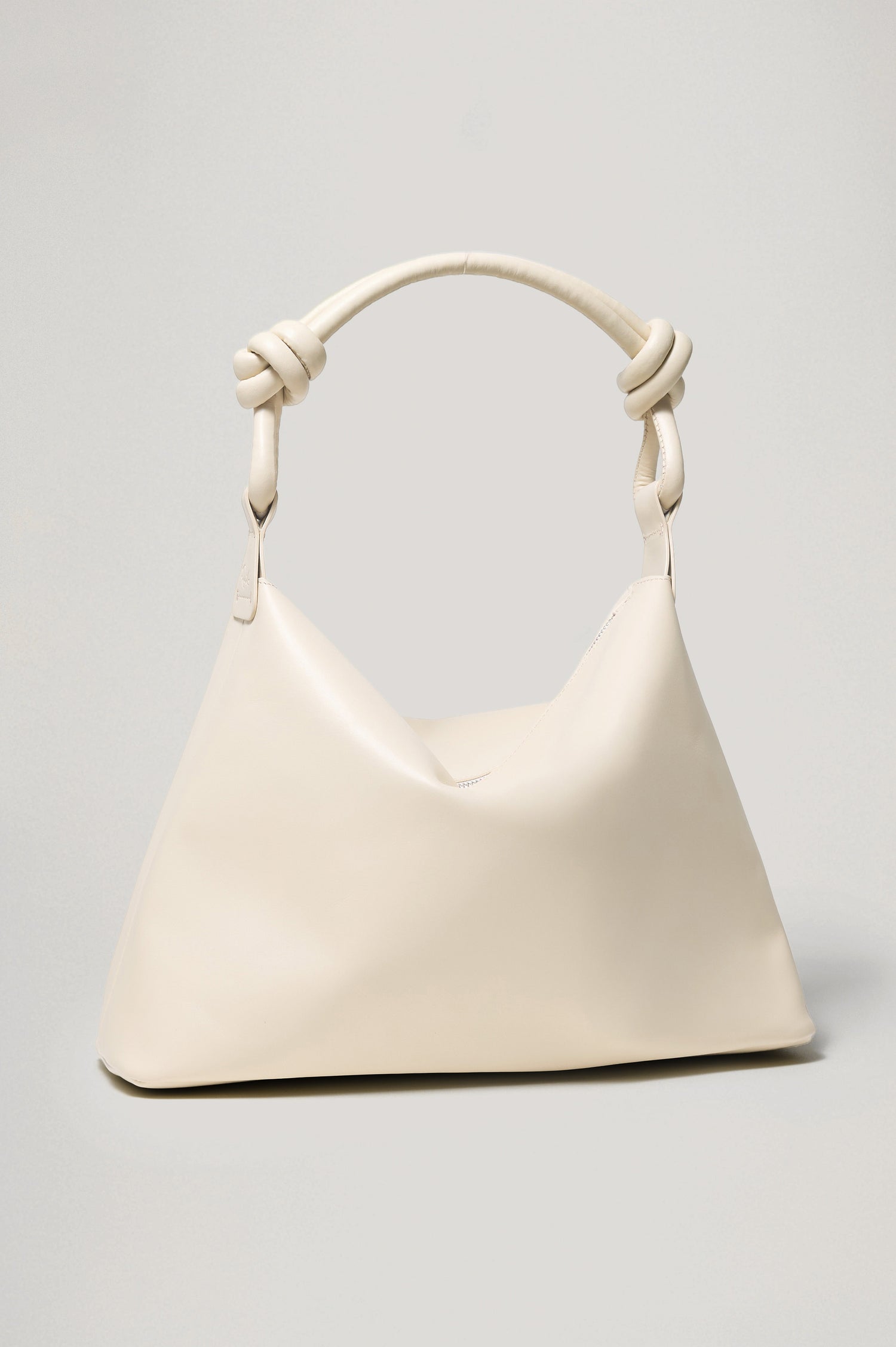 The Siena is a true slouchy hobo bag, crafted from smooth leather with a knotted top strap and a zip closure finished with a fringed tassel. In Bone Leather Colorway. Front view featured.