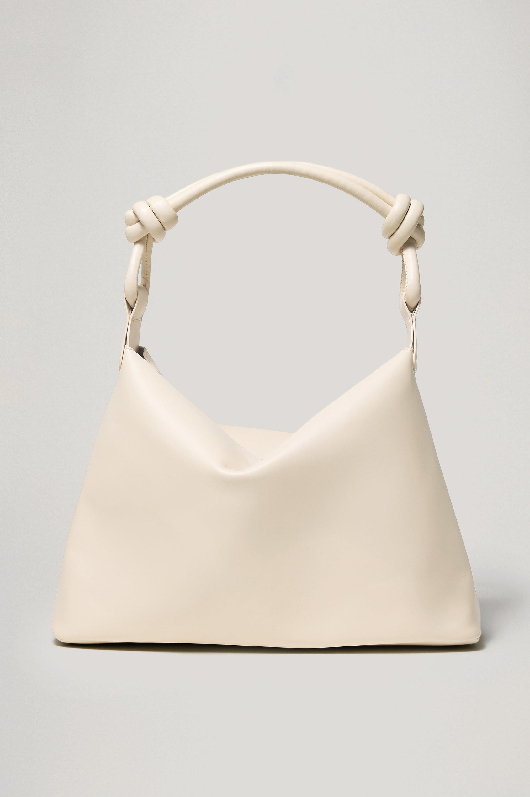The Siena is a true slouchy hobo bag, crafted from smooth leather with a knotted top strap and a zip closure finished with a fringed tassel. In Bone Leather Colorway. Front view featured.