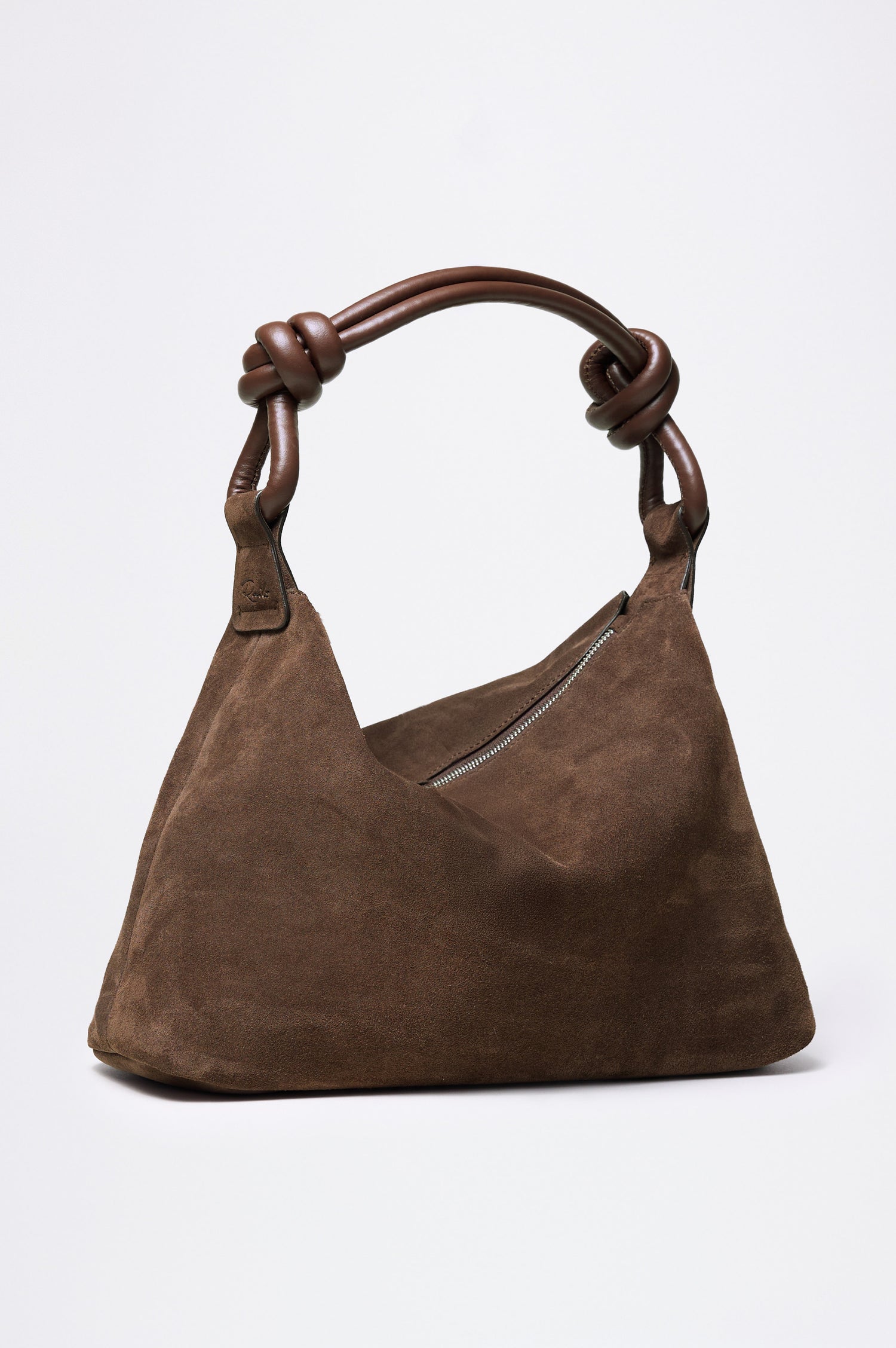 The Siena is a true slouchy hobo bag, crafted from smooth leather with a knotted top strap and a zip closure finished with a fringed tassel. In Espresso Suede Colorway. Front view featured.