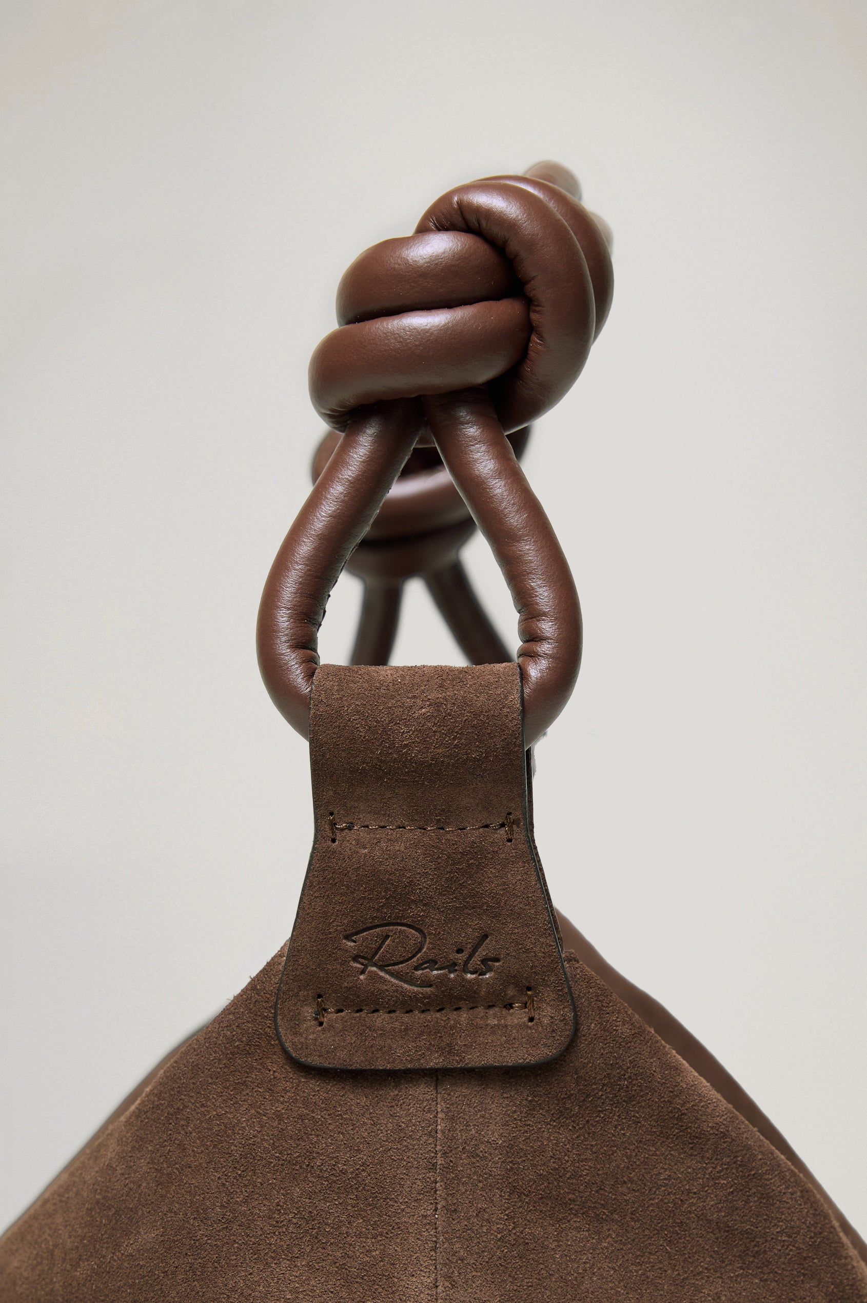 Siena Slouchy Hobo Bag in Suede With Knotted Top Strap, Zipper Closure With Fringe Tassel And Interior Snap Button Slip Pocket in Espresso Suede Colorway - Side Close Up Branded Detail View Featured