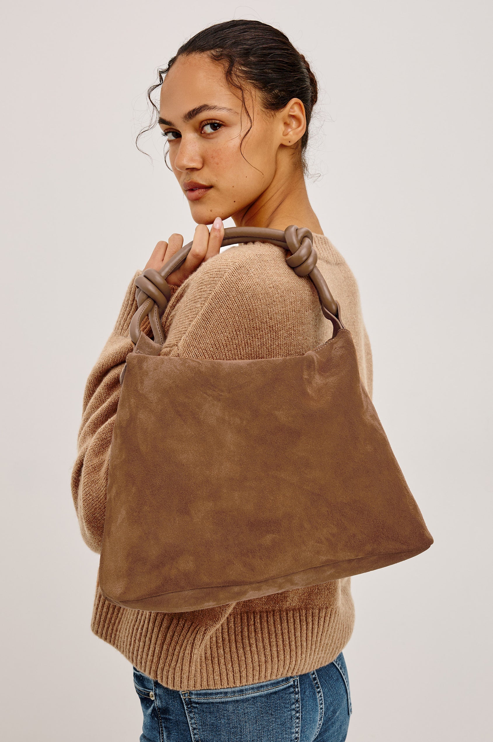 Siena Hobo Bag in Suede With Knotted Top Strap, Zip Closure With Fringe Tassel Pull, Microsuede Lining, Snap-Button Slip Pocket and Foil Logo Stamp at Interior in Camel Suede Colorway - Side View Featured on Model