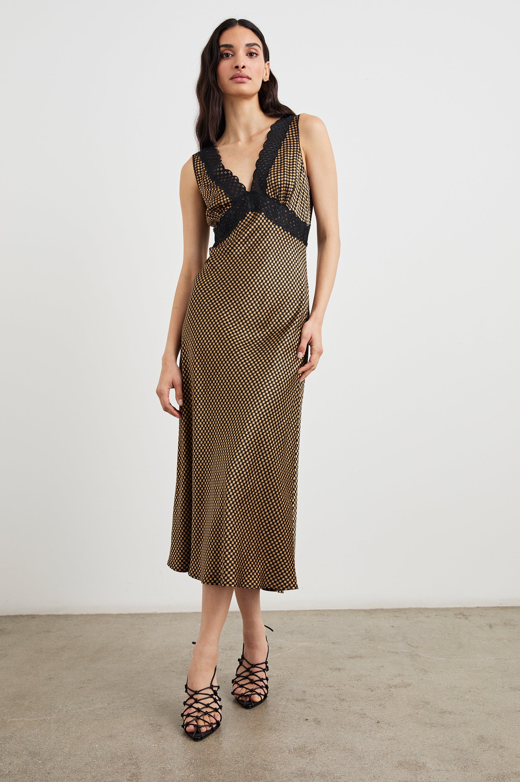 Simona Sleeveless Midi Dress with a Deep V Neck and Black Lace Crossover Trim on the Bodice in Gold Houndstooth Colorway - Front Full Body View Featured on Model
