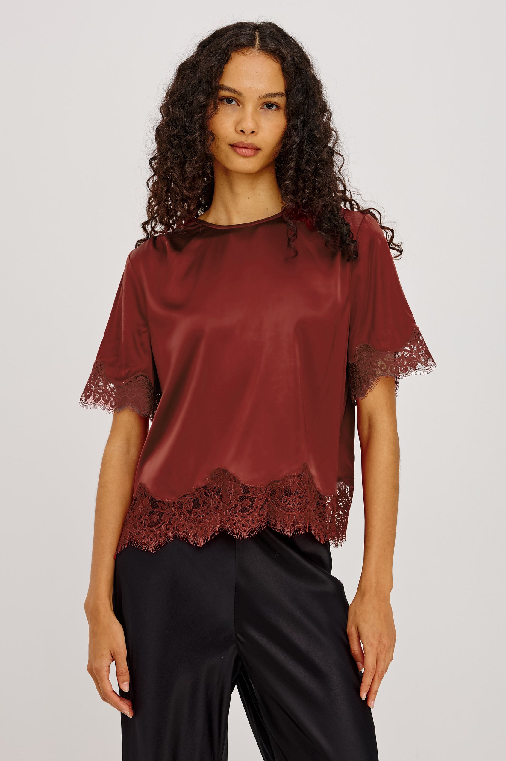 Sonora Shirt in Satin Blend With Loose Boxy Fit, Crew Neck, Shirred Shoulders, Short Sleeves, Button-Loop Back Keyhole, and Lace Trim in Crimson Colorway - Upper Body Front View Featured on Model
