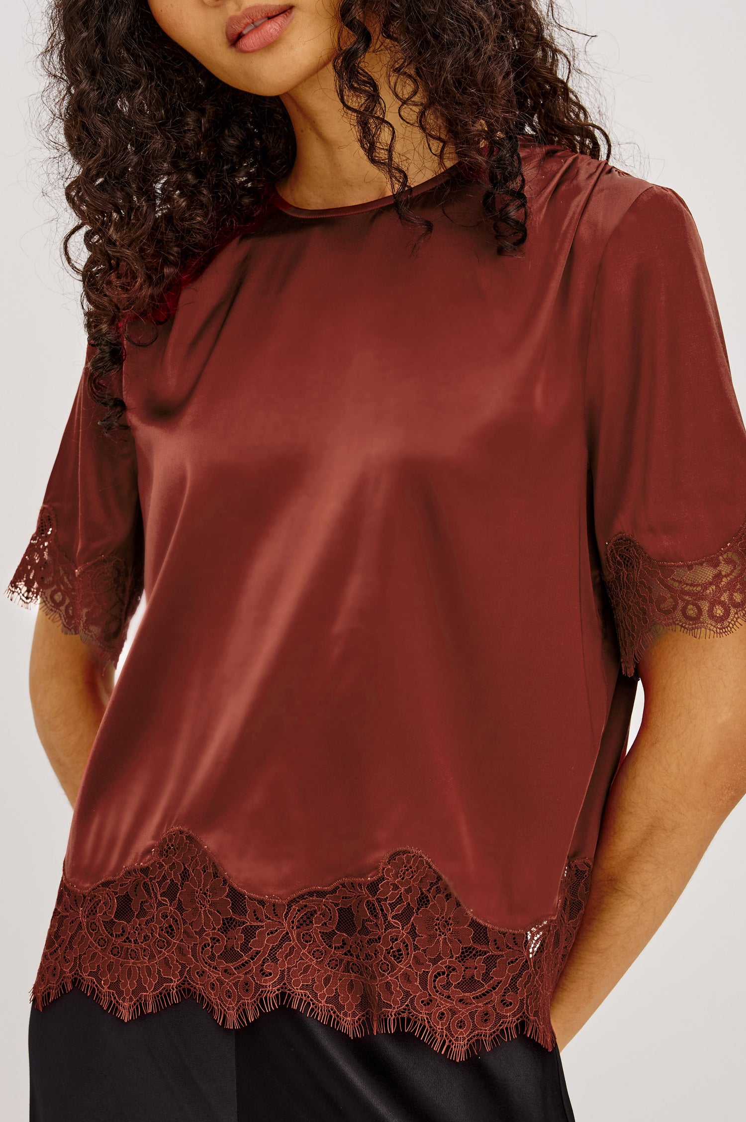 Sonora Shirt in Satin Blend With Loose Boxy Fit, Crew Neck, Shirred Shoulders, Short Sleeves, Button-Loop Back Keyhole, and Lace Trim in Crimson Colorway - Upper Body Front Close Up View Featured on Model