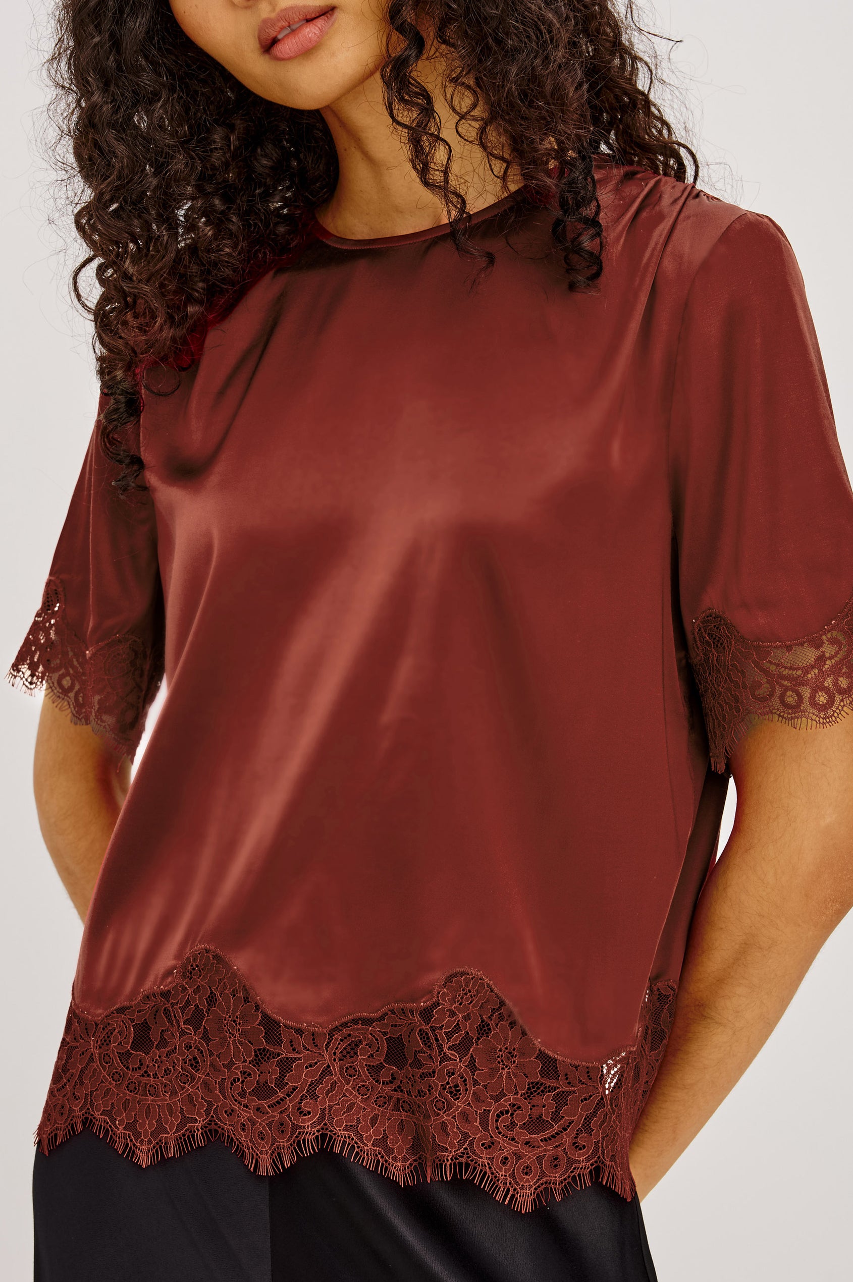 Sonora Shirt in Satin Blend With Loose Boxy Fit, Crew Neck, Shirred Shoulders, Short Sleeves, Button-Loop Back Keyhole, and Lace Trim in Crimson Colorway - Upper Body Front Close Up View Featured on Model