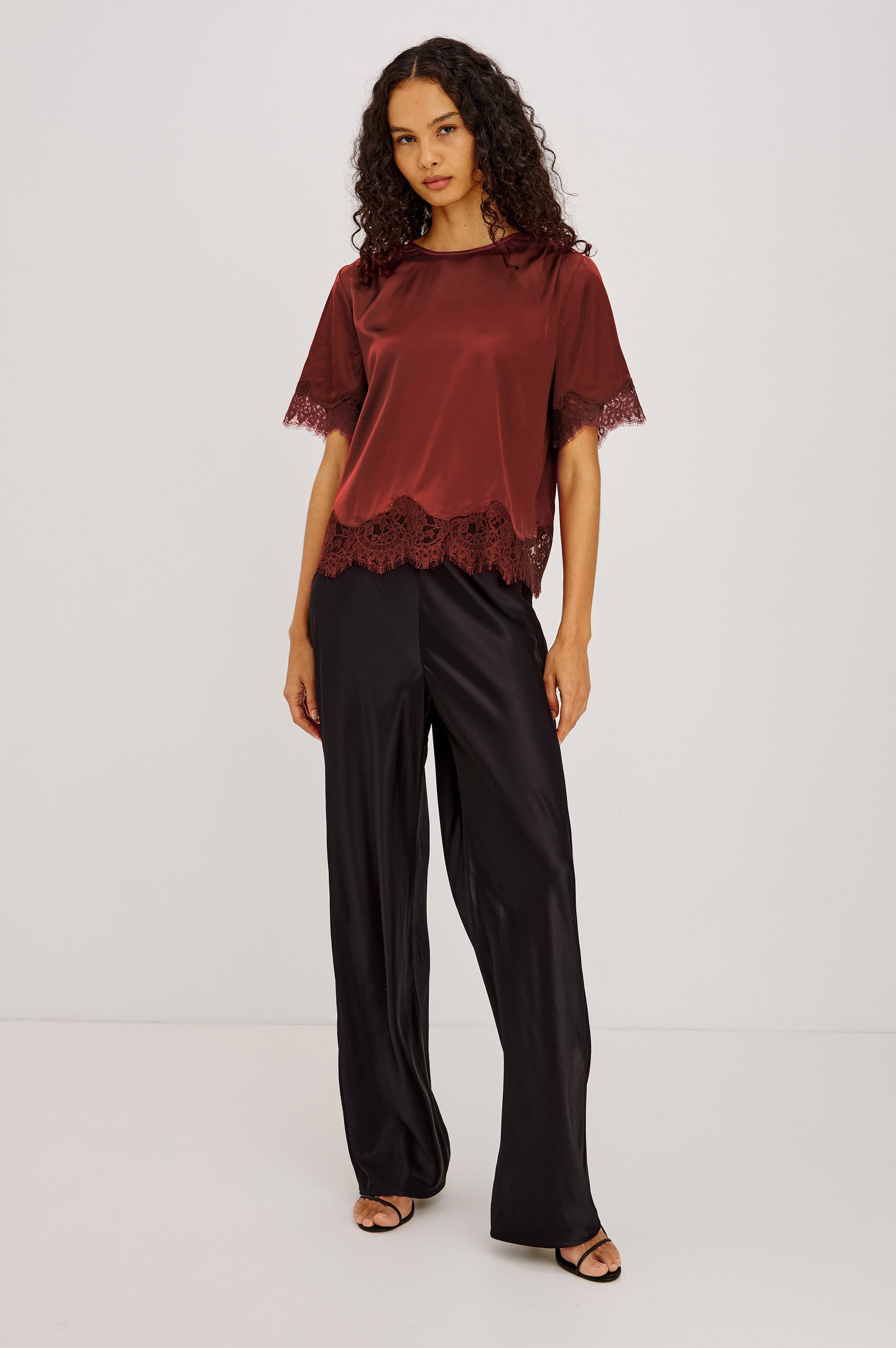 Sonora Shirt in Satin Blend With Loose Boxy Fit, Crew Neck, Shirred Shoulders, Short Sleeves, Button-Loop Back Keyhole, and Lace Trim in Crimson Colorway - Full Body Front View Featured on Model