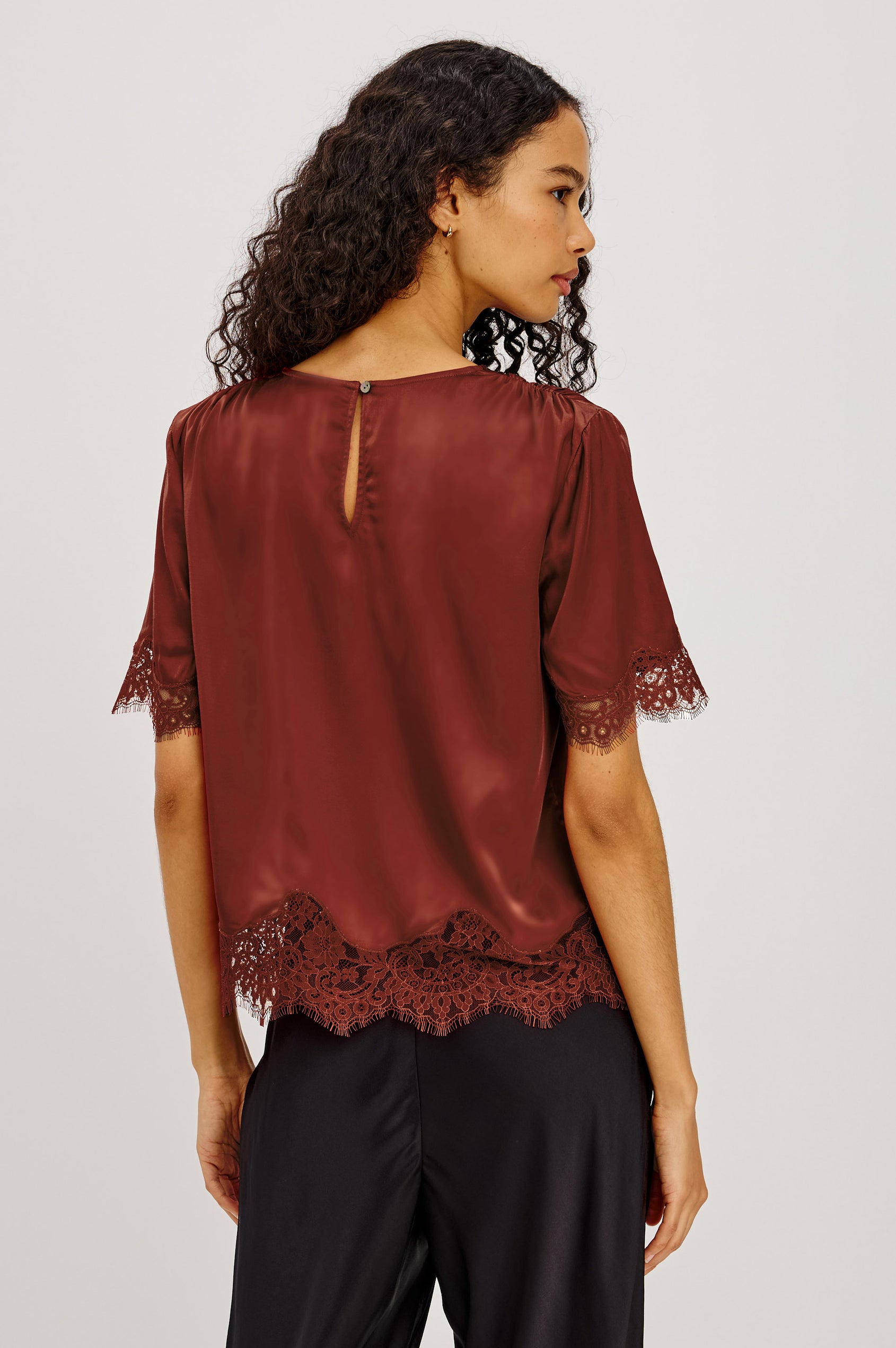 Sonora Shirt in Satin Blend With Loose Boxy Fit, Crew Neck, Shirred Shoulders, Short Sleeves, Button-Loop Back Keyhole, and Lace Trim in Crimson Colorway - Upper Body Back View Featured on Model
