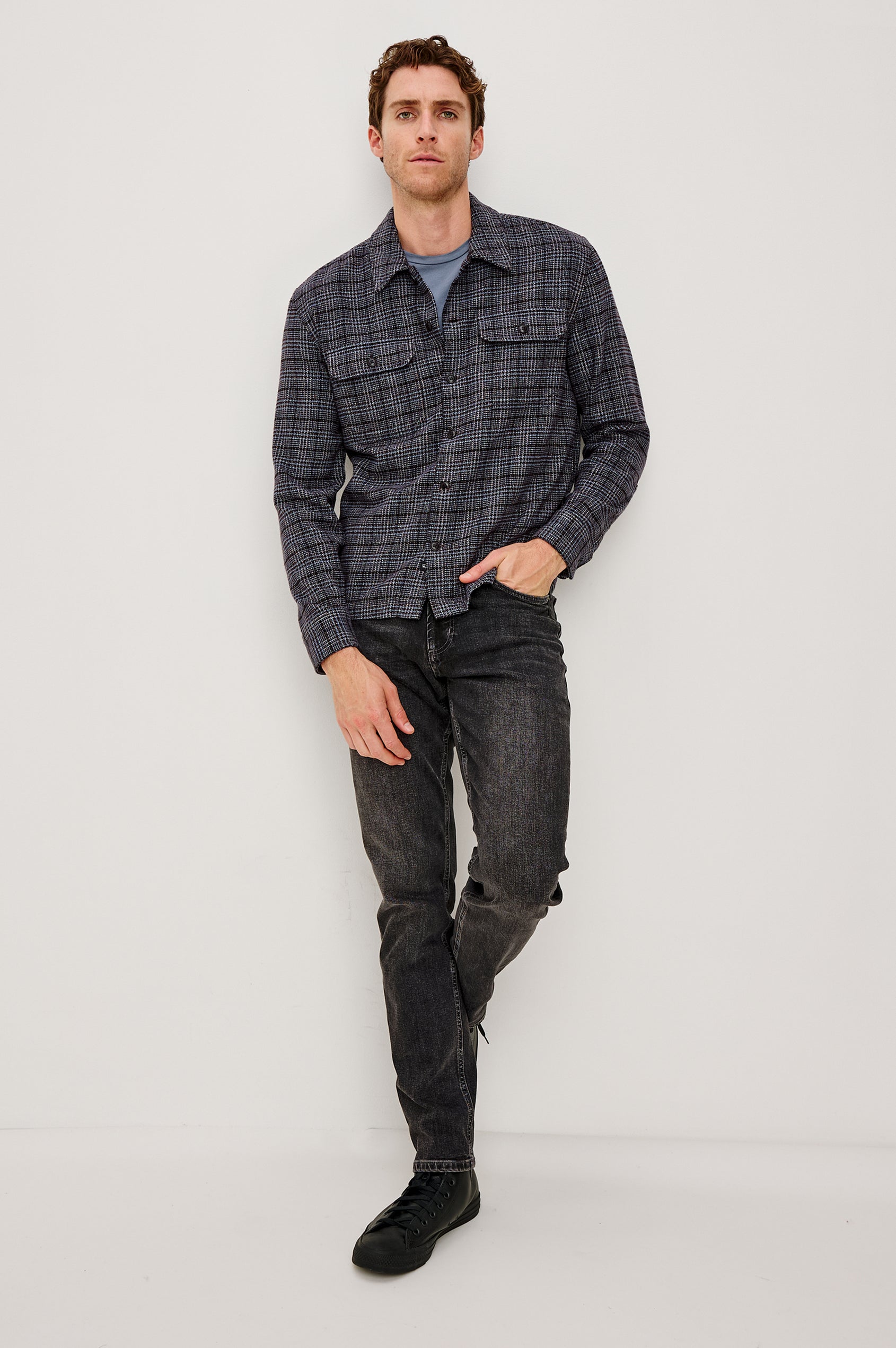 Stellan is a shirt jacket made from heavy brushed cotton with a classic collar, front button closures, chest flap pockets in Cedar Bay, a blue and grey plaid colorway. Front full body view featured on model.