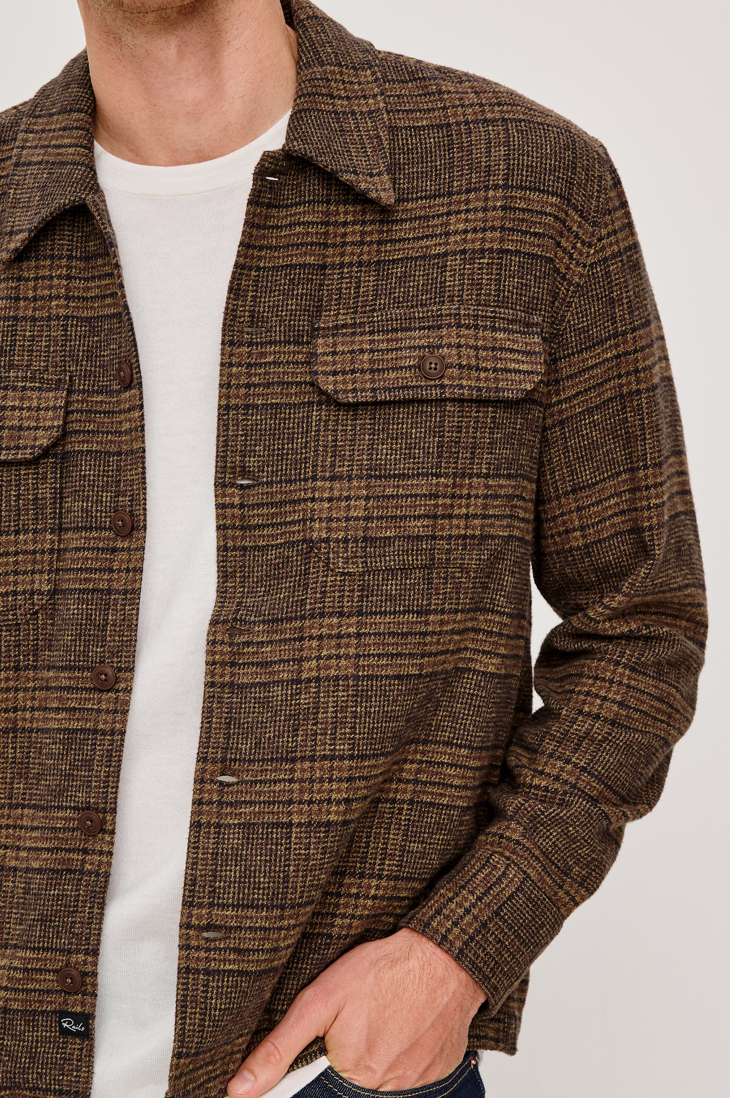 Stellan is a shirt jacket made from heavy brushed cotton with a classic collar, front button closures, chest flap pockets in Cedar Bay, a blue and grey plaid colorway. Front detail view featured on model.