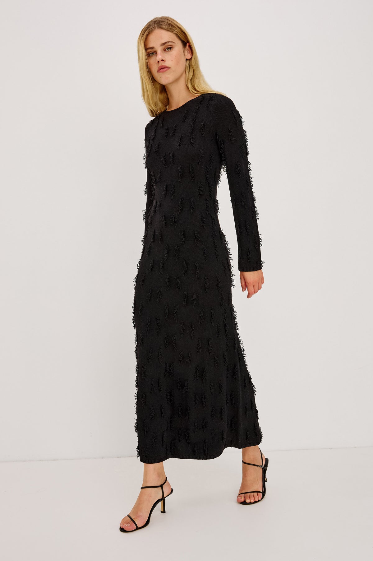 Sulma Maxi Dress Knit in Soft Fine-Gauge Yarn With Alover Fringe, Slim Fit Through Bodice and Long Sleeves, and A-Line Skirt in Black Colorway - Front Full Body View Featured on Model.