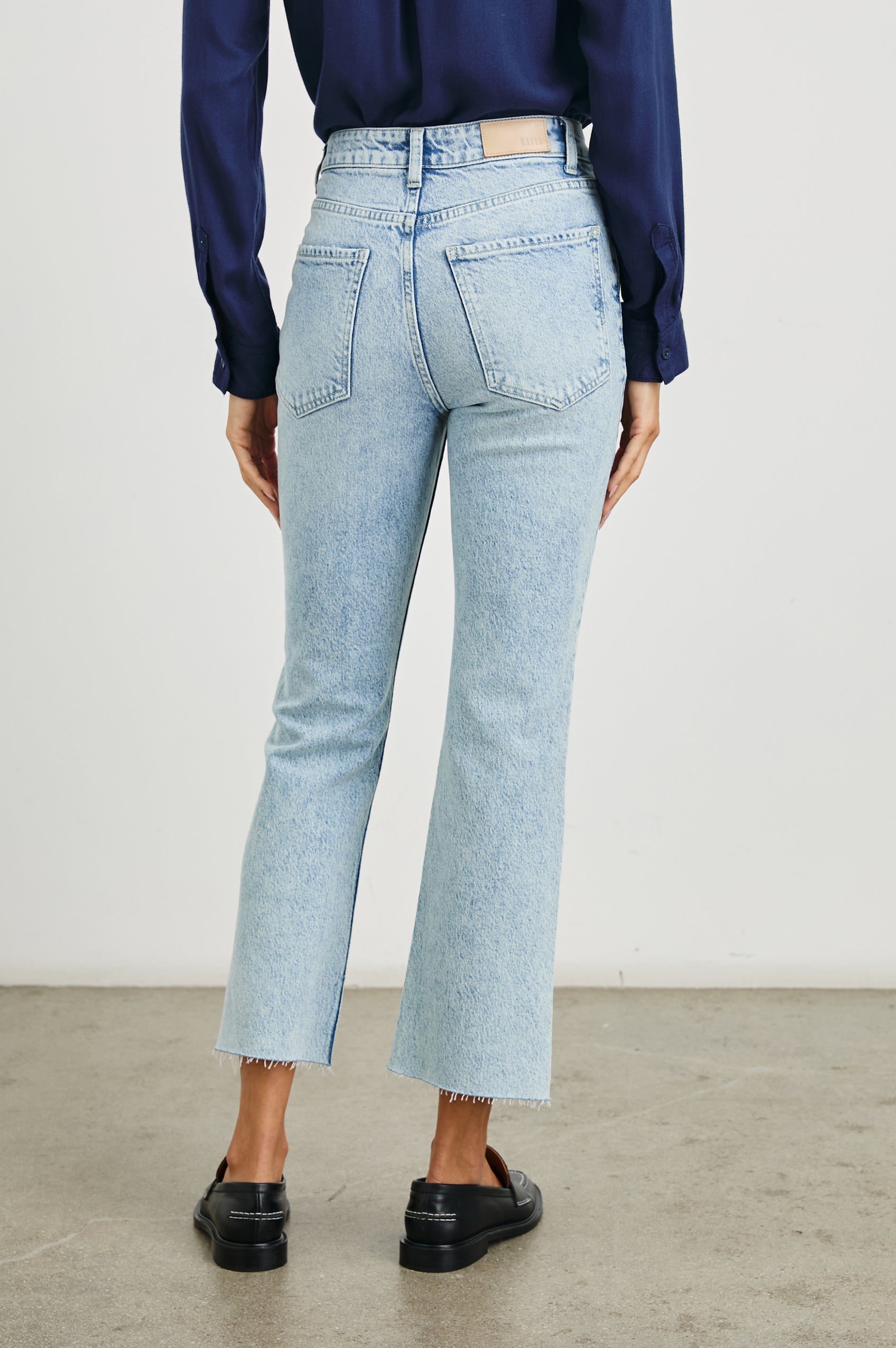 Sunset Crop Slim Fare Jeans with a Raw Hem, Belt Loops, Two Front Pockets plus a Coin Pocket and Two Back Patch Pockets in Snowbird Colorway - Back View Featured on Model