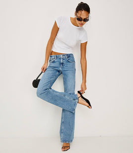 Woman wearing a white t-shirt and blue jeans on a plain background
