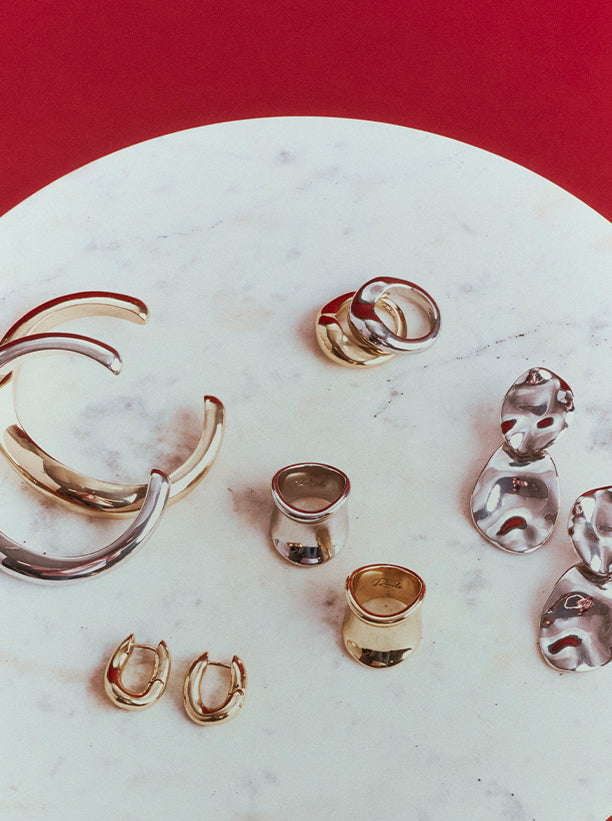 Variety of rings, earrings, and bracelets positioned on a textured marble surface