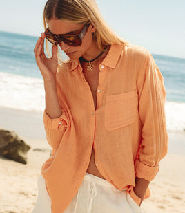 Woman wearing an orange shirt and sunglasses on a beach