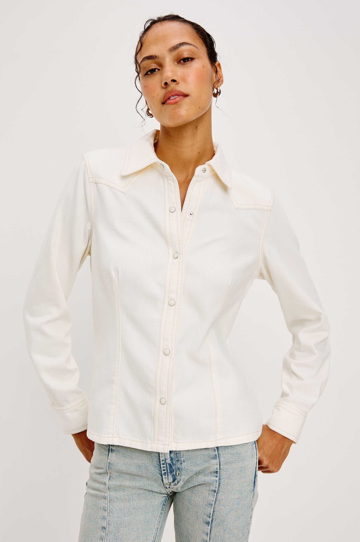 Taiana Shirt in Cotton Lyocell Denim With Collar Front and Back Darting Western Yoke Front Snap Buttons Long Sleeves and Fitted Silhouette in Ivory Colorway - Upper Body Front View Featured on Model