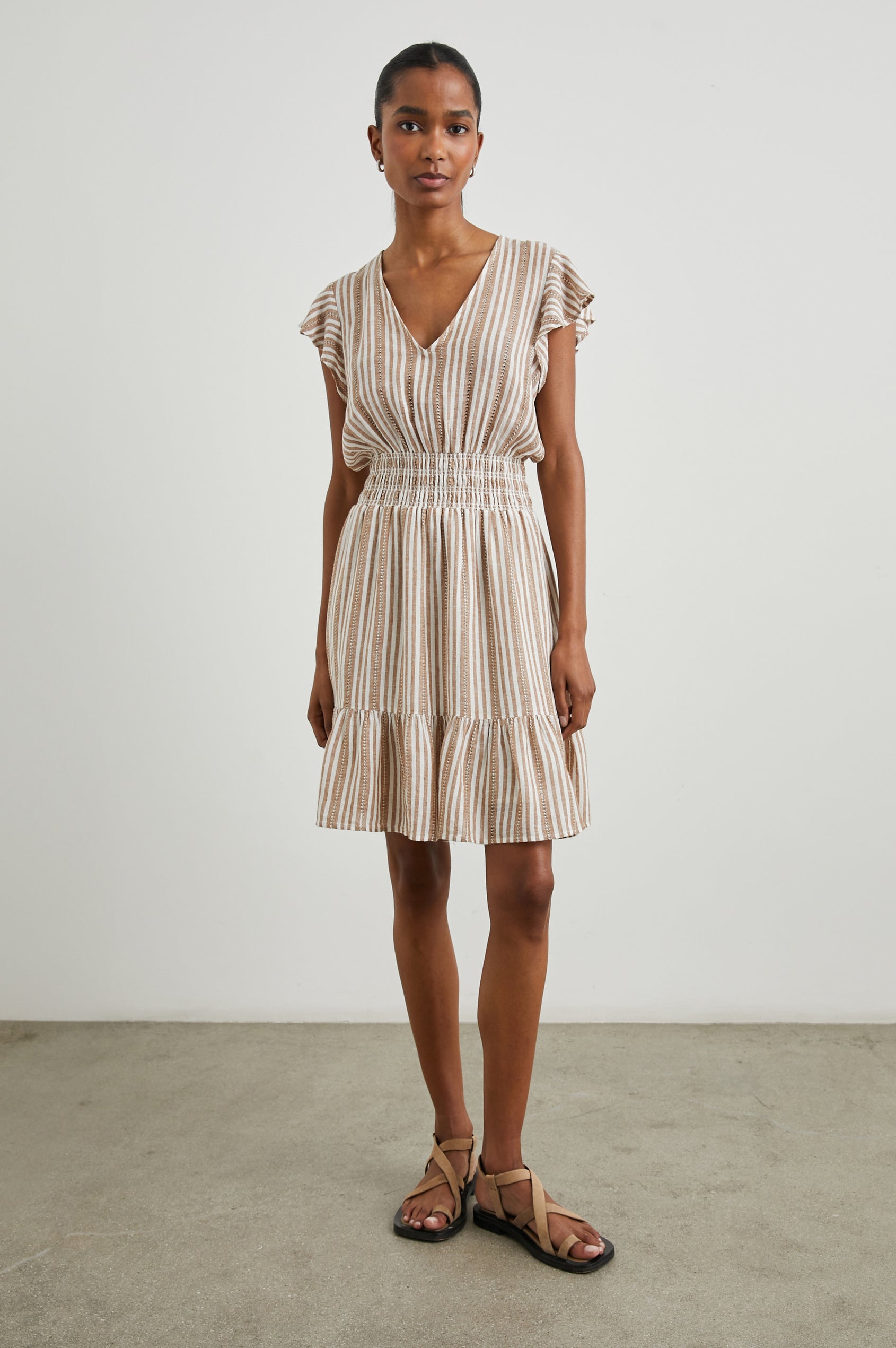 Tara Short Sleeve, Above the Knee Dress with a Smocked Waist, V Neck, Flutter Cap Sleeves, and Tiered Skirt with a Ruffled Hem in Palo Santo Stripe Colorway, with Textured Brown Vertical Stripes on White - Front Full Body View Featured on Model 