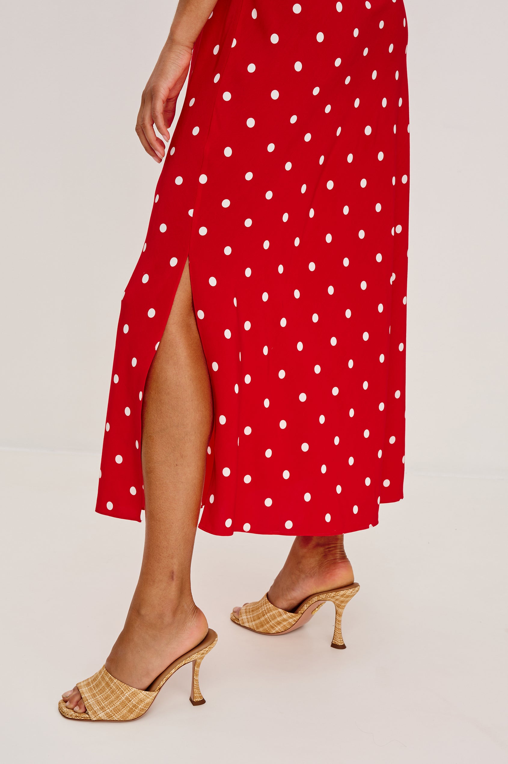 Terena midi dress in Rossa colorway featuring a V neckline, polka dot pattern and fabricated rose at the front chest - close up of skirt details on model