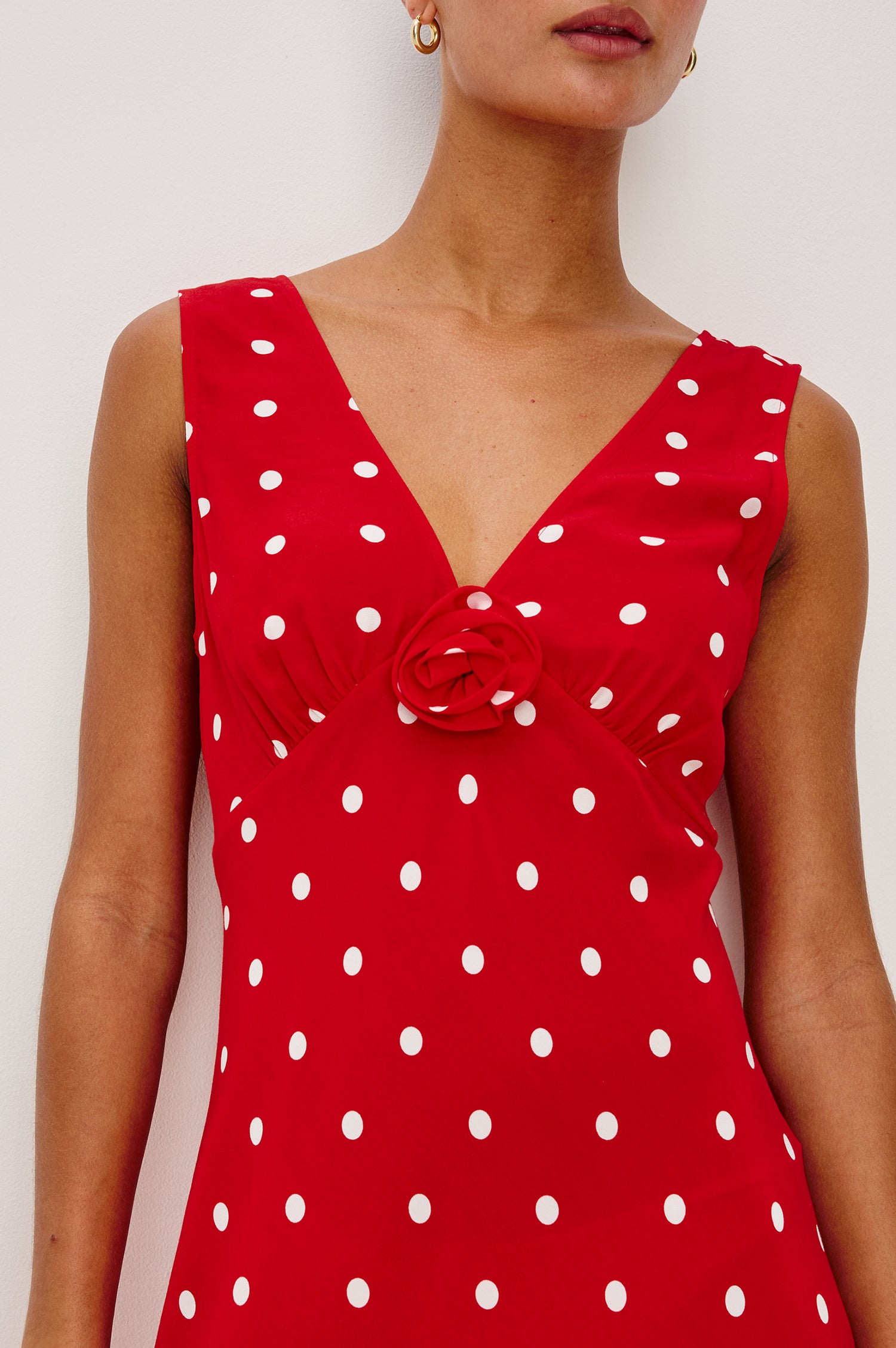 Terena midi dress in Rossa colorway featuring a V neckline, polka dot pattern and fabricated rose at the front chest - close up of details on model