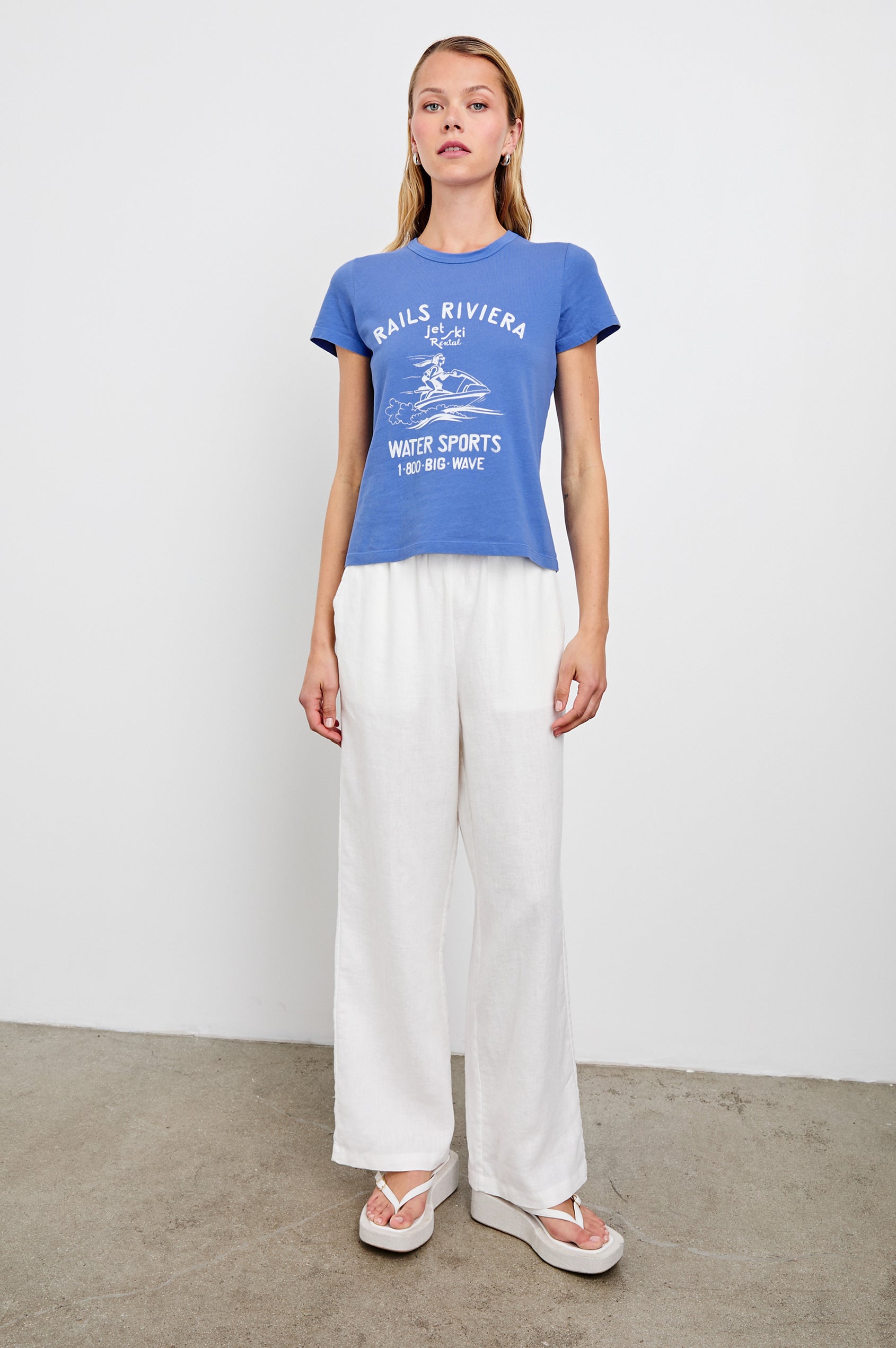 Fitted Crew T-Shirt with a jet ski image and the text Rails Riviera jet ski Rental Water Sports 1 800 Big Wave in Rails Riviera Colorway, White Text on Blue - Front Full Body View Featured on Model