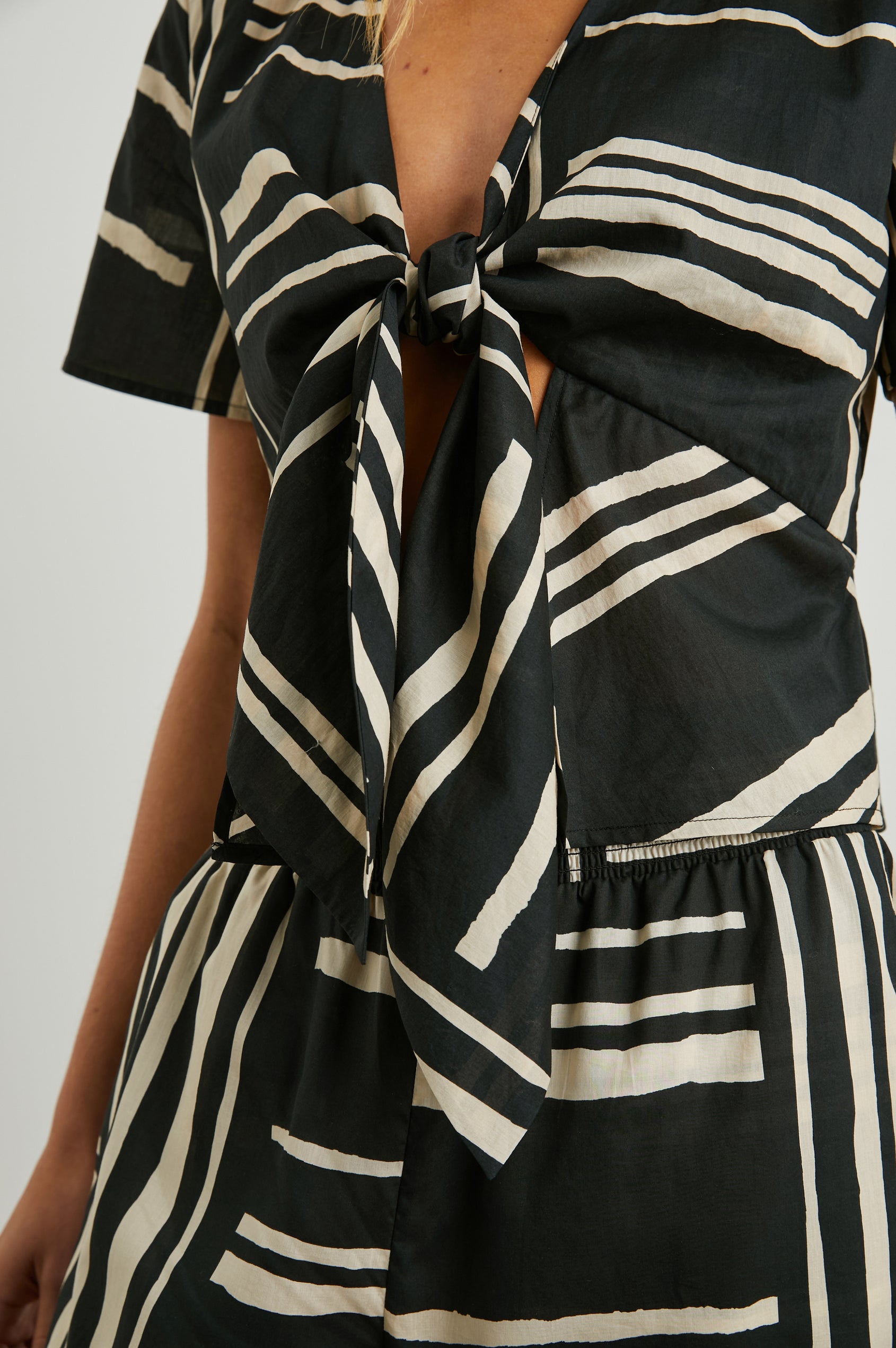 Tia Short-Sleeve Top Closed with a Front Tie and a Deep V Neck in Island Stripe Colorway, Cream Horizontal and Vertical Stripes on Black - Front View Featured on Model