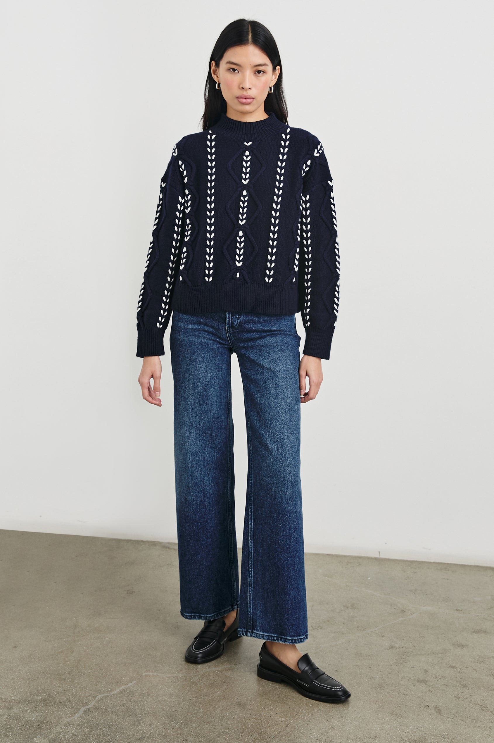 Tori Long-Sleeve Cable Sweater with a Mock Neck, Ribbed Trim in Midnight Colorway, with Thick White Vertical Stitches - Front Full Body View Featured on Model 