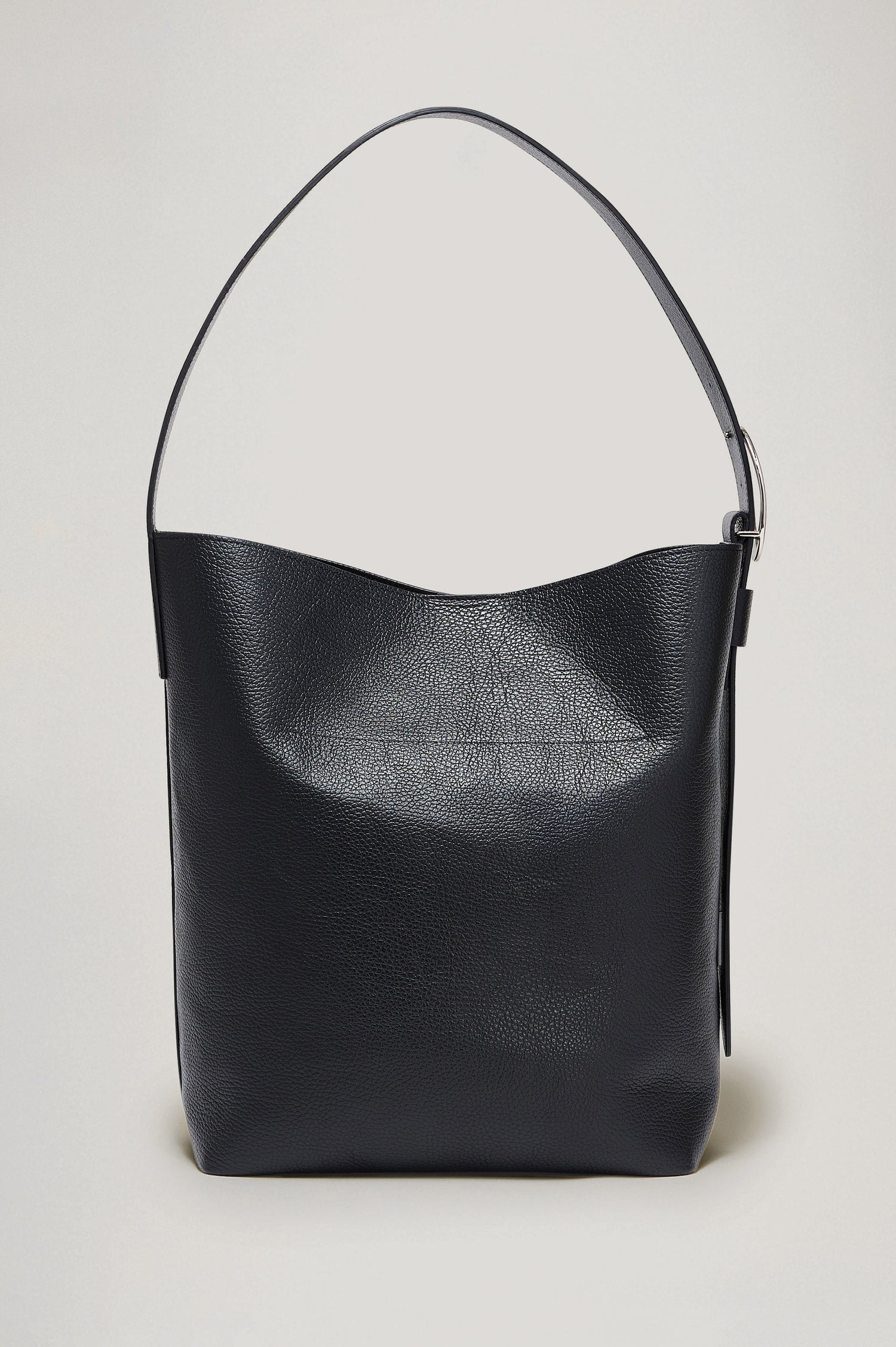 Torino Bucket Bag in Italian Pebbled Leather With Adjustable Strap and Polished Silver Oval Buckle, Microsuede Lining, Interior Magnetic Closure, Snap Button-Slip Pocket, and Subtle Branded Detailing in Black Colorway - Side Close Up Branded Detail View Featured