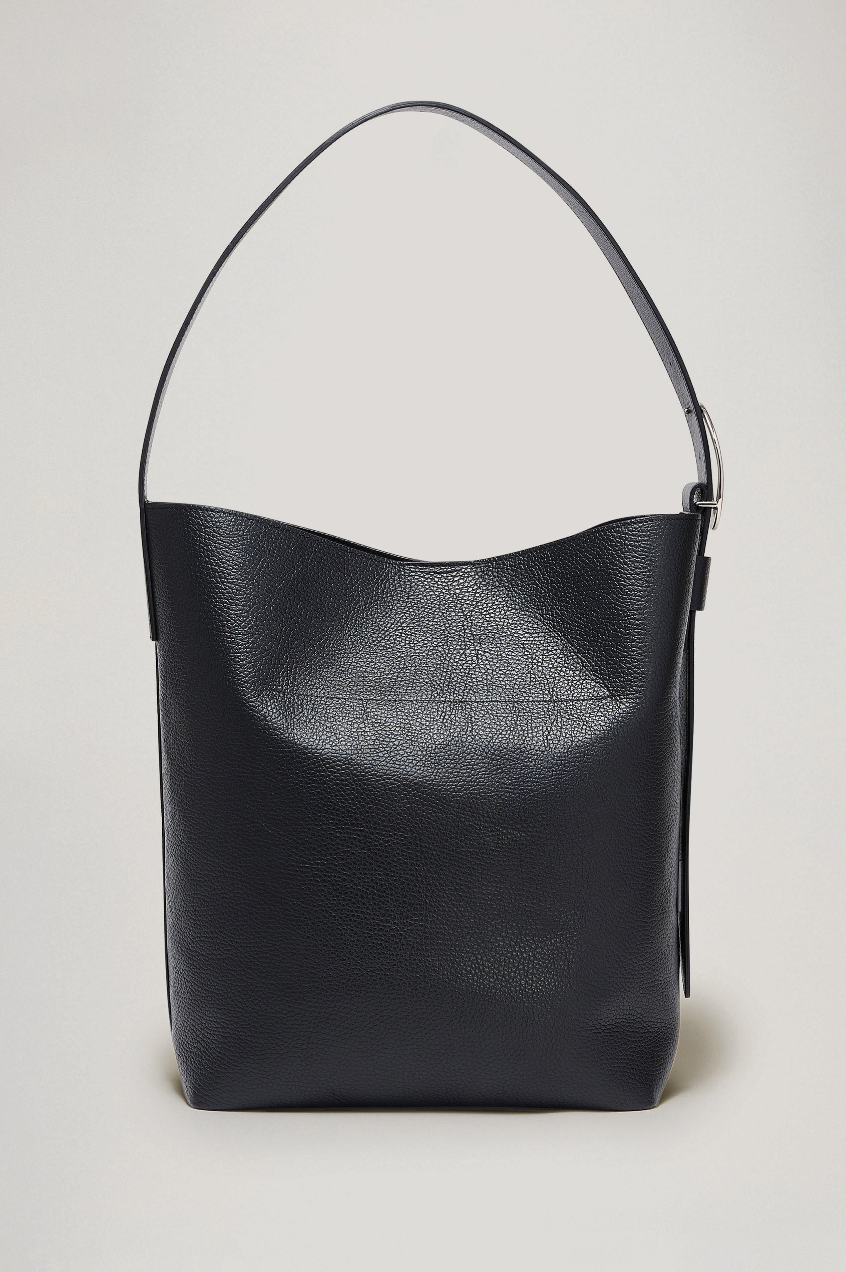 Torino Bucket Bag in Italian Pebbled Leather With Adjustable Strap and Polished Silver Oval Buckle, Microsuede Lining, Interior Magnetic Closure, Snap Button-Slip Pocket, and Subtle Branded Detailing in Black Colorway - Side Close Up Branded Detail View Featured