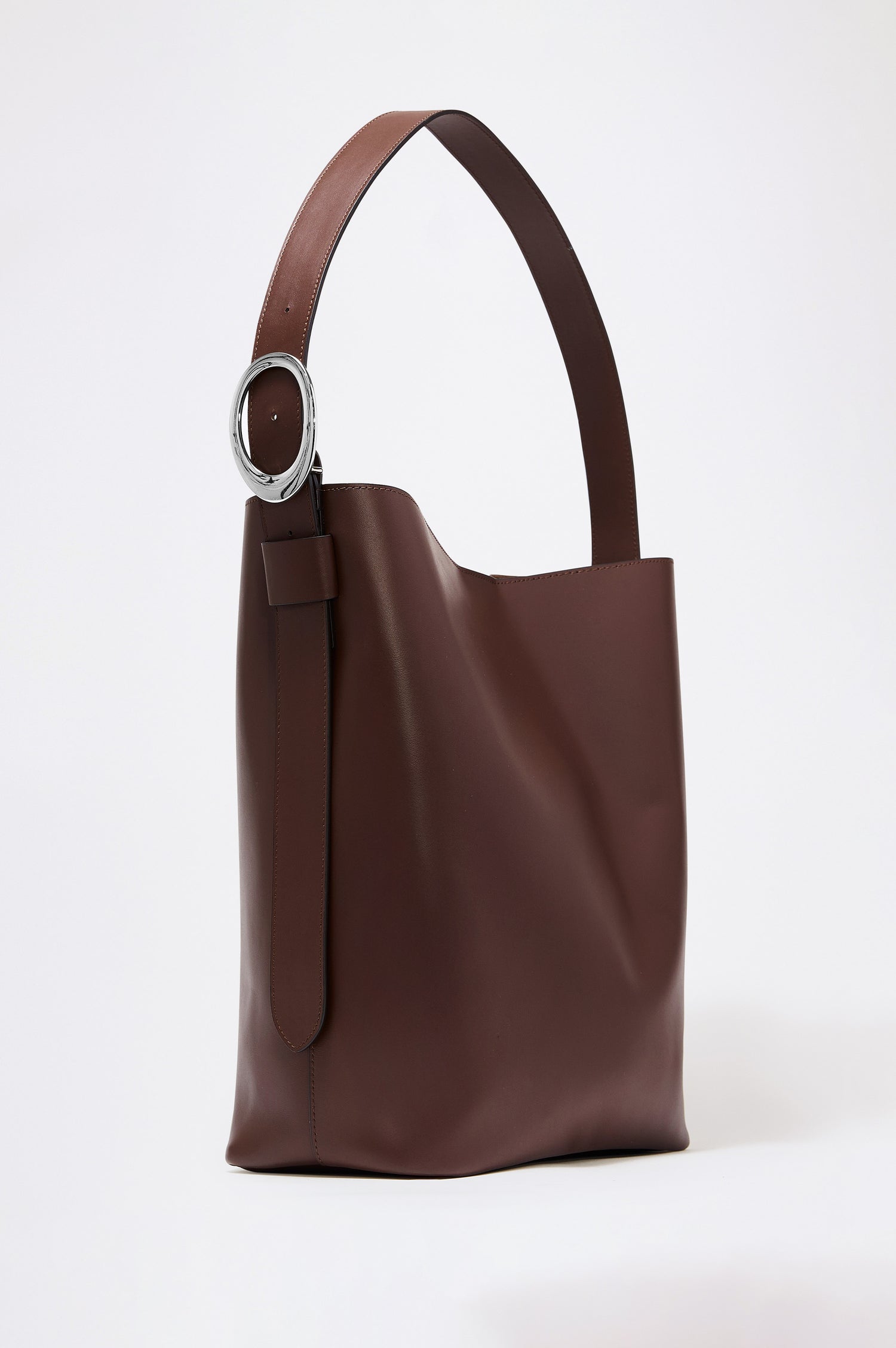 The Torino is a soft leather bucket bag, designed with an adjustable strap and polished silver oval buckle, in espresso colorway. Front view featured.