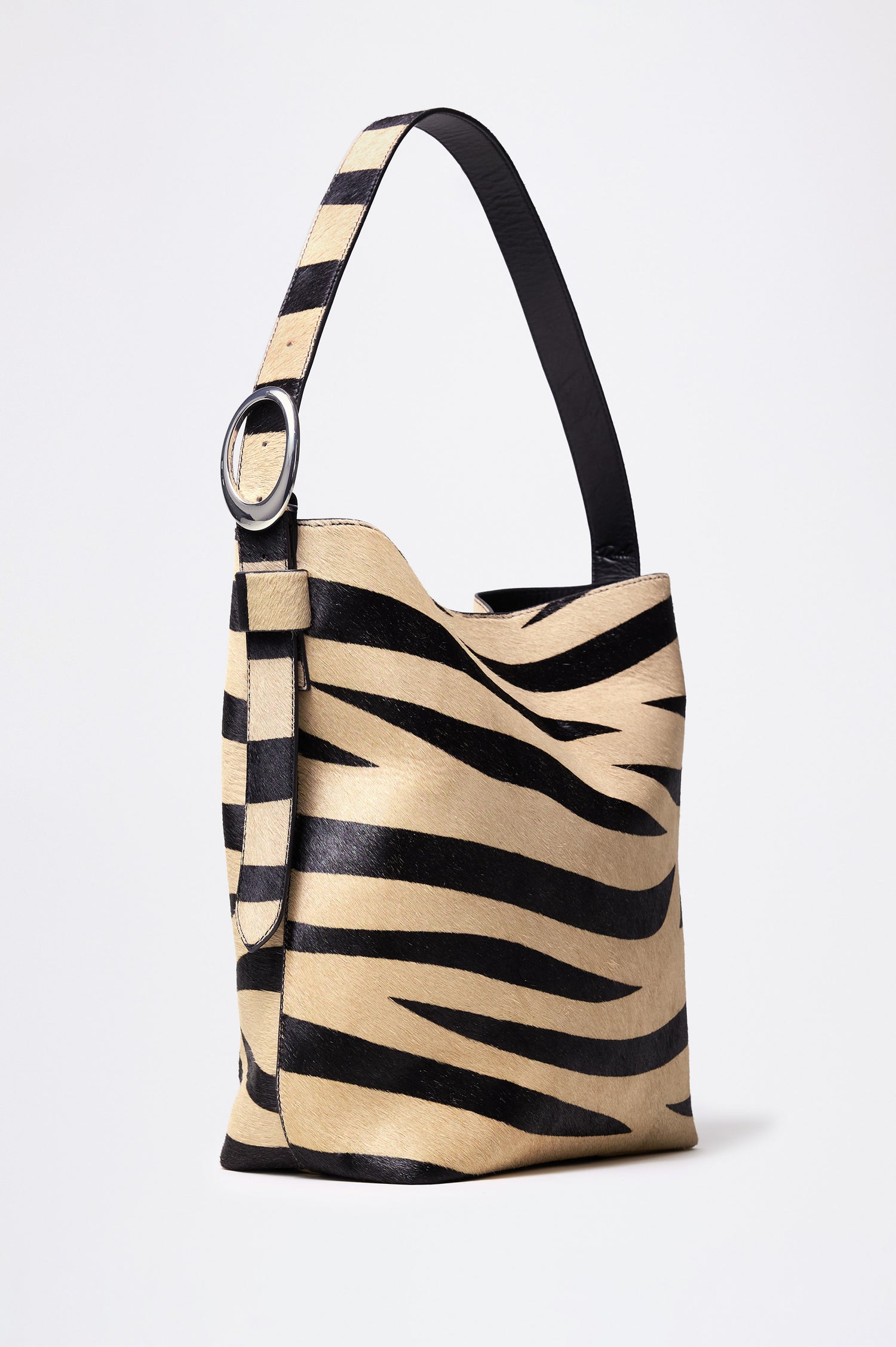 The Torino is a zebra-print haircalf leather bucket bag, designed with an adjustable strap and polished silver oval buckle. Front view featured.