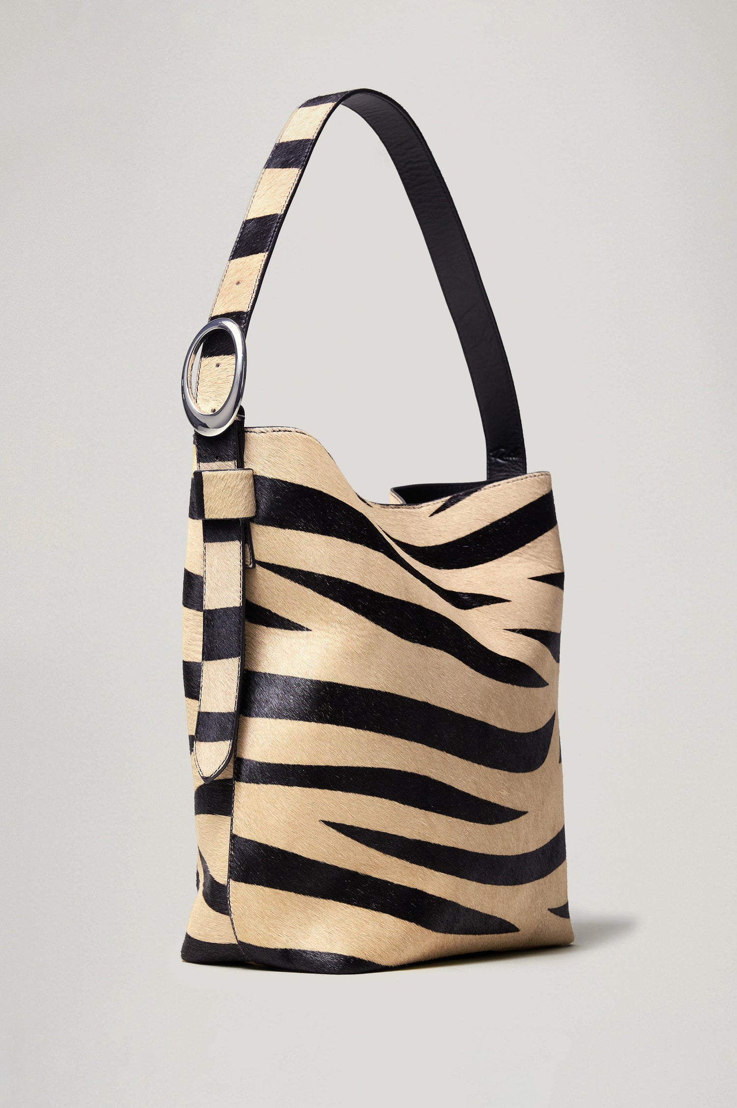 Torino Bucket Bag in Zebra Print Haircalf With Adjustable Strap and Polished Silver Oval Buckle, Microsuede Lining, Interior Magnetic Closure, Snap Button-Slip Pocket, and Subtle Branded Detailing in Zebra Haircalf Colorway - Front View Featured