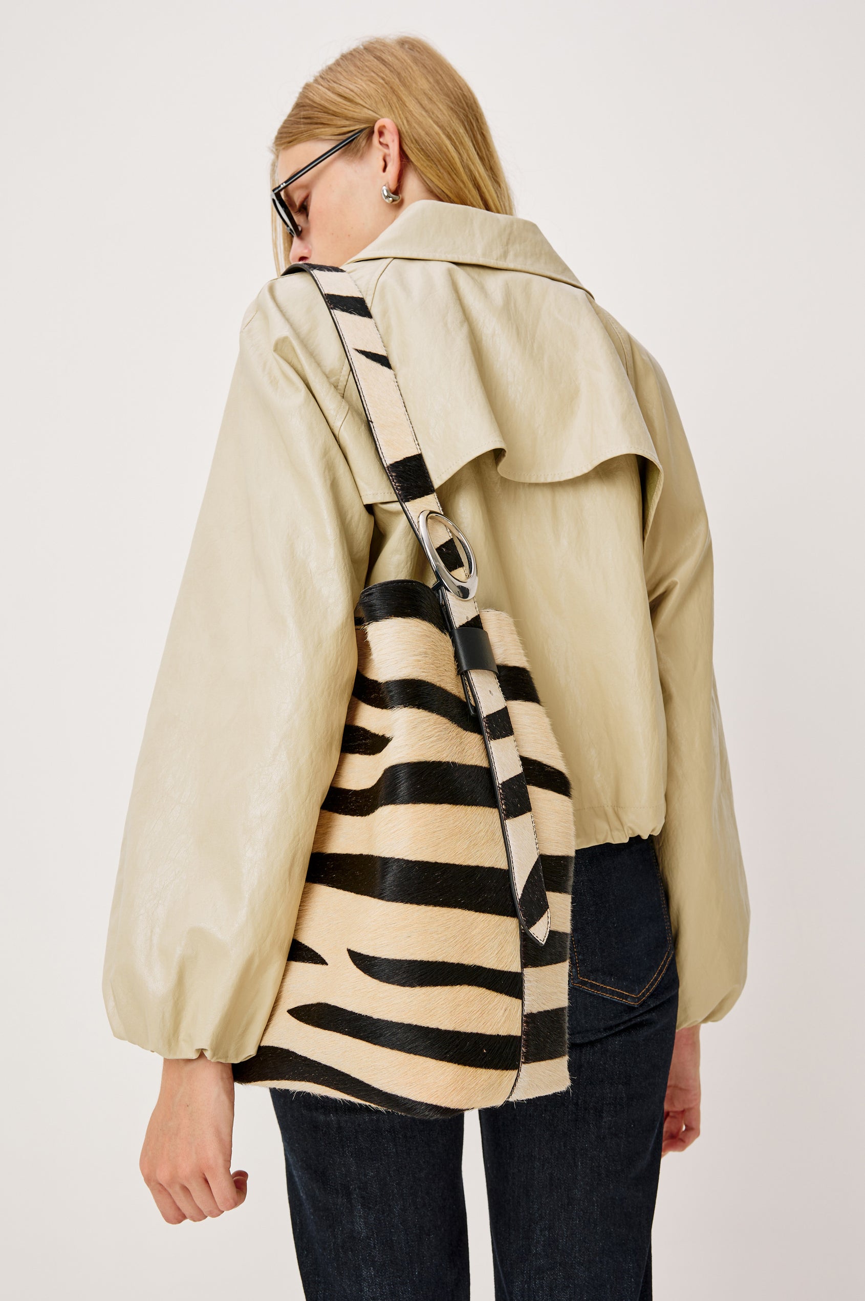 The Torino is a zebra-print haircalf leather bucket bag, designed with an adjustable strap and polished silver oval buckle. Back view featured on model.