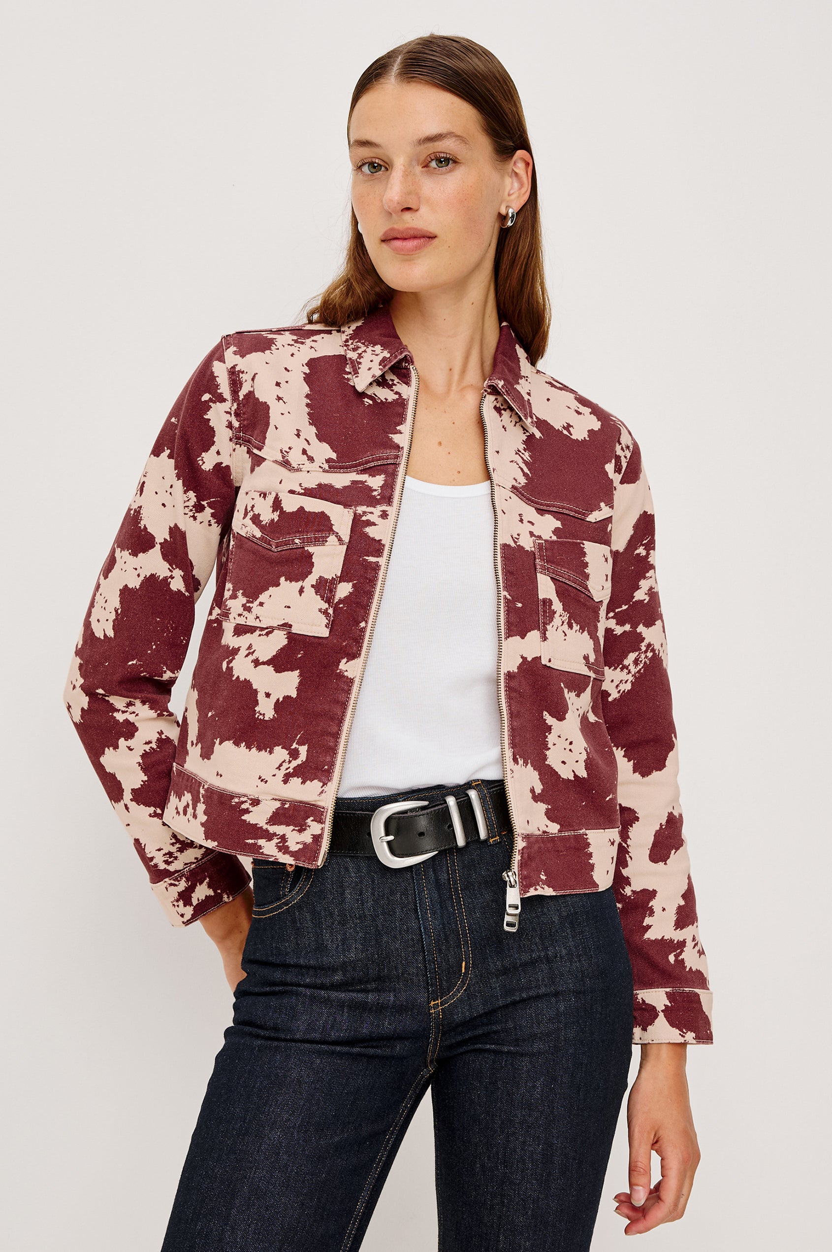 The Trabuco is a collared two-way zip front jacket with two chest pockets and a western style yoke in Cowgirl colorway - a red and beige cow print. Front view featured on model.