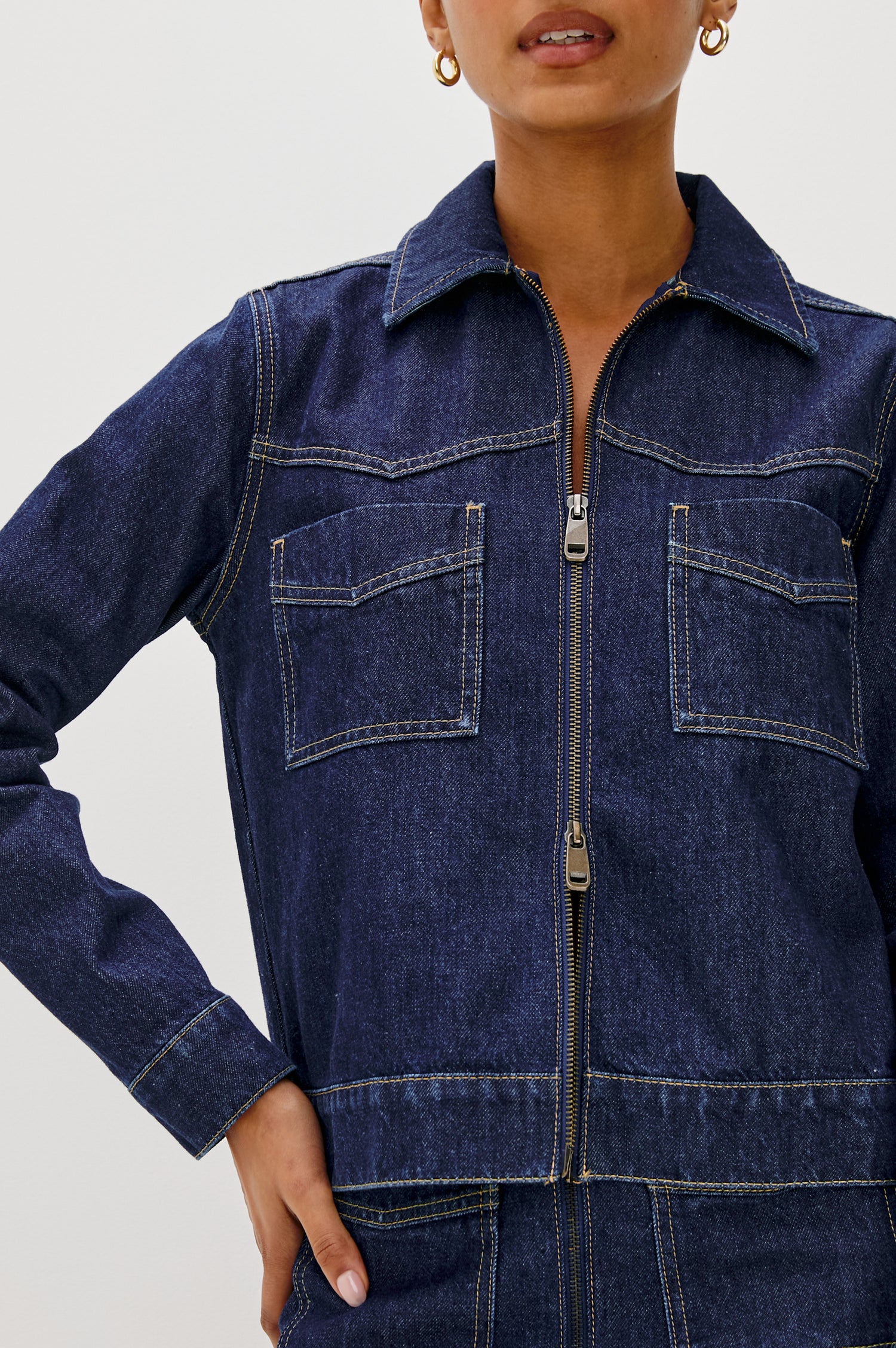 The Trabuco is a collared two-way zip front jacket with two chest pockets and a western style yoke in Deep Indigo colorway - a rinse denim wash. Front detail view featured on model.
